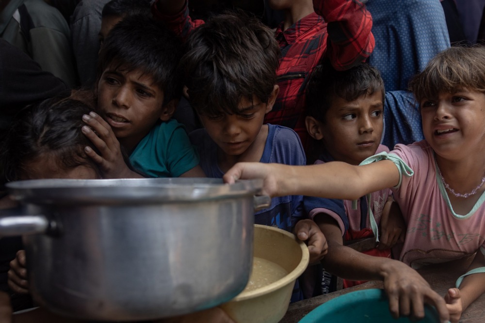 Internally displaced Palestinians gather outside a charity kitchen in Gaza city to receive limited food