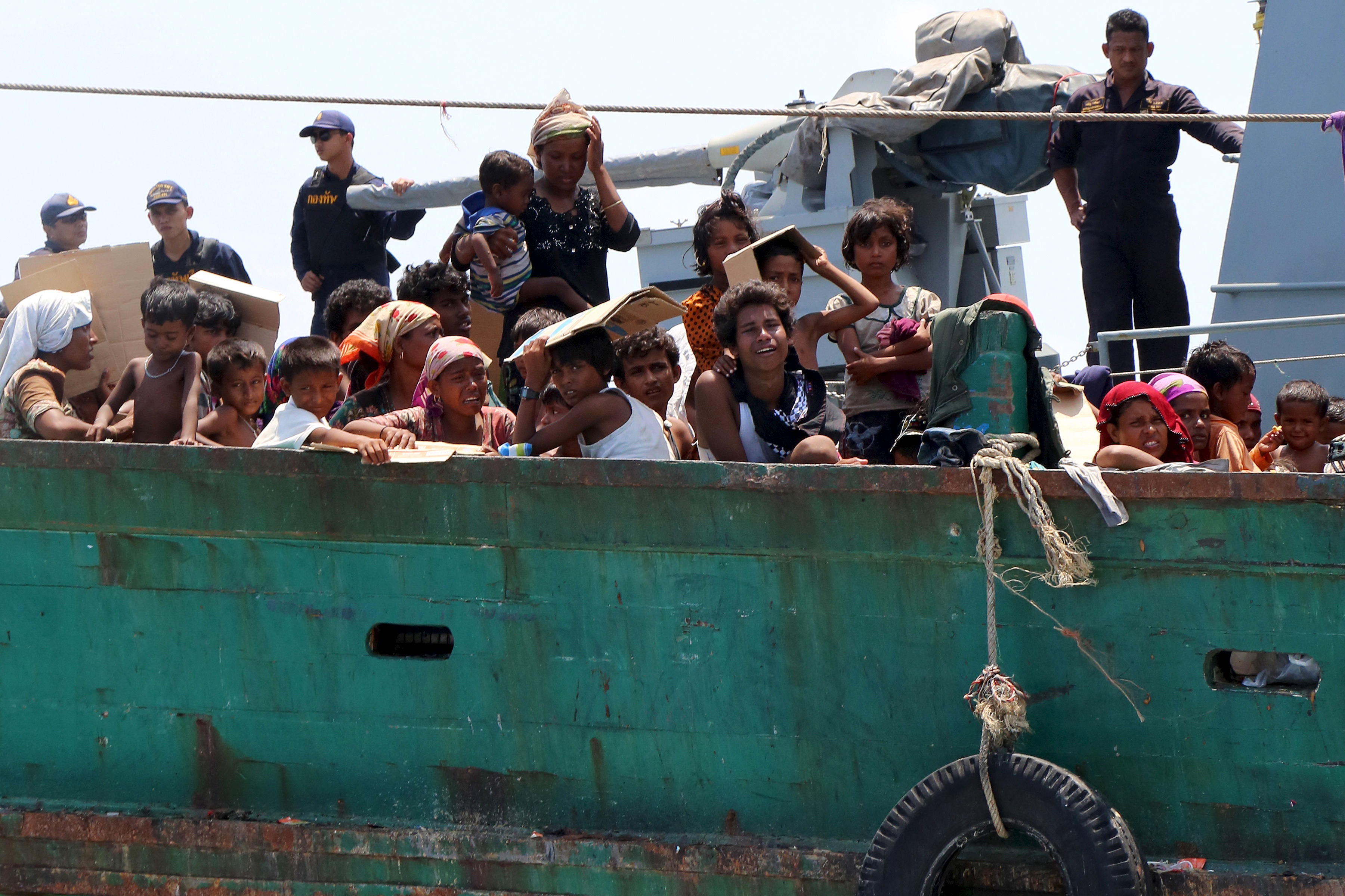 Navy officers look at migrants as their boat is towed away from Thailand by a Thai navy vessel, in waters near Koh Lipe island, May 16, 2015. Malaysian vessels on Saturday intercepted a boat crammed with migrants after the Thai navy towed it away from Thailand, the latest of a number of vessels pushed back to sea by governments who have ignored a U.N. call for an immediate rescue. An estimated 25,000 Bangladeshis and Rohingya boarded smugglers' boats in the first three months of this year, twice as many in the same period of 2014, the UNHCR has said. REUTERS/Aubrey Belford