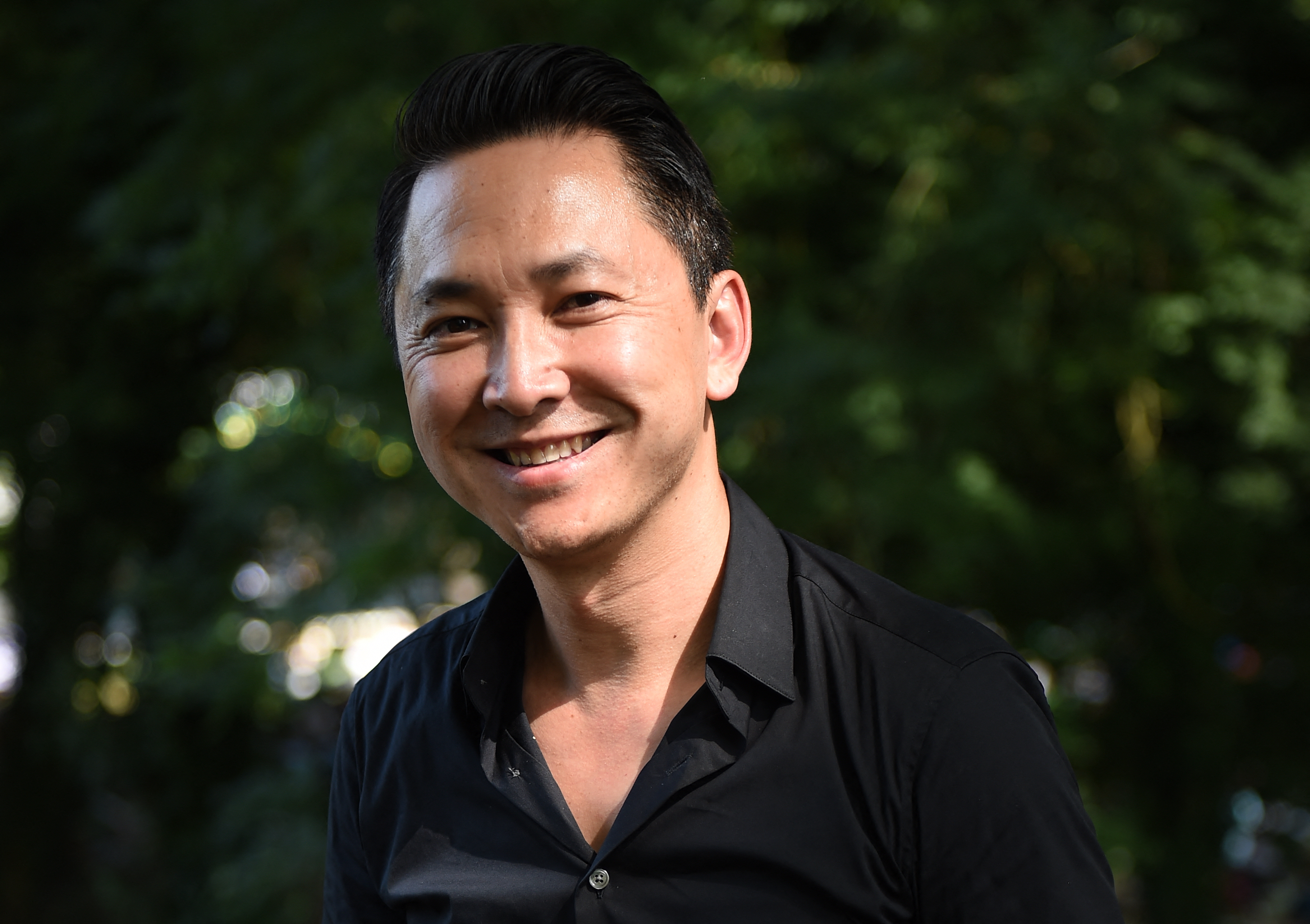 A portrait of Viet Thanh Nguyen against a leafy background.