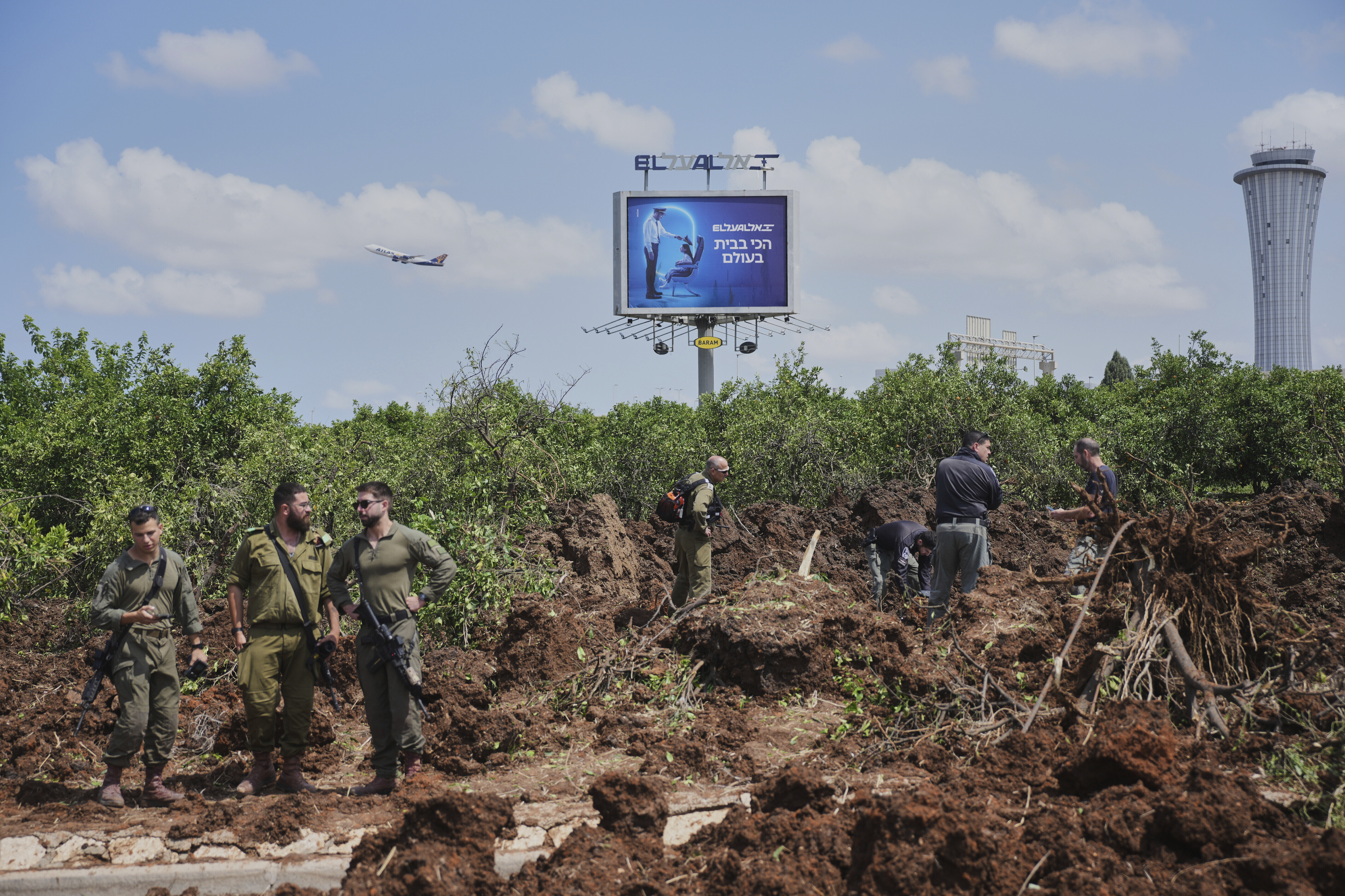 Israeli security forces inspect the site where the Israeli military said a projectile fired by Yemen's Houthi rebels landed in the area of Ben Gurion International Airport near Tel Aviv, Israel