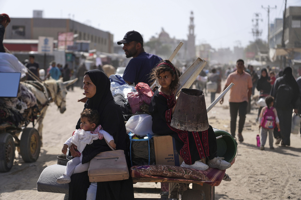 Displaced Palestinians sit in the back of a cart