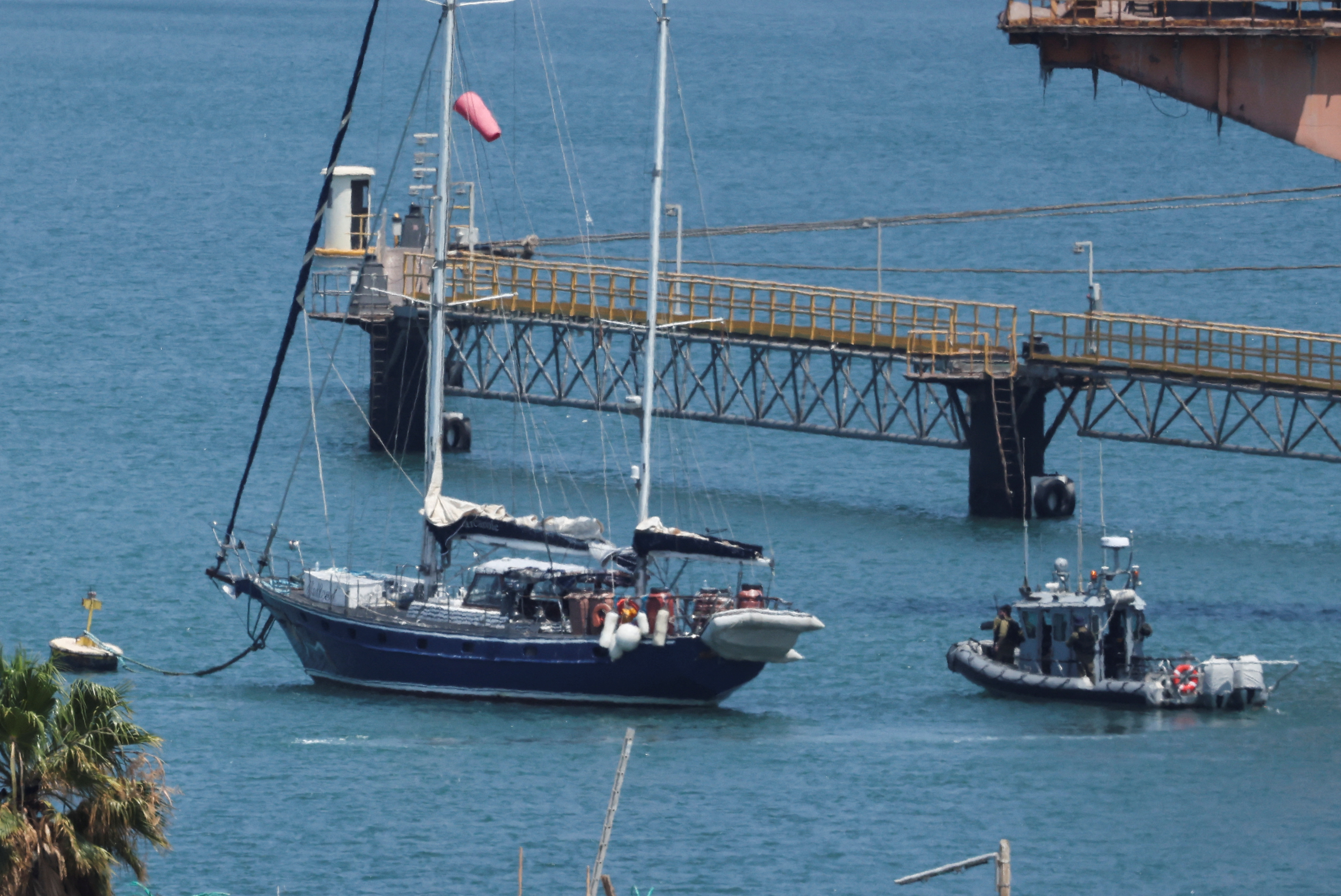 Gaza-bound British-flagged yacht "Madleen" is docked next to a military boat Ashdod port following a takeover by the Israeli army, in Ashdod, Israel, June 10, 2025 [Nir Elias/Reuters]