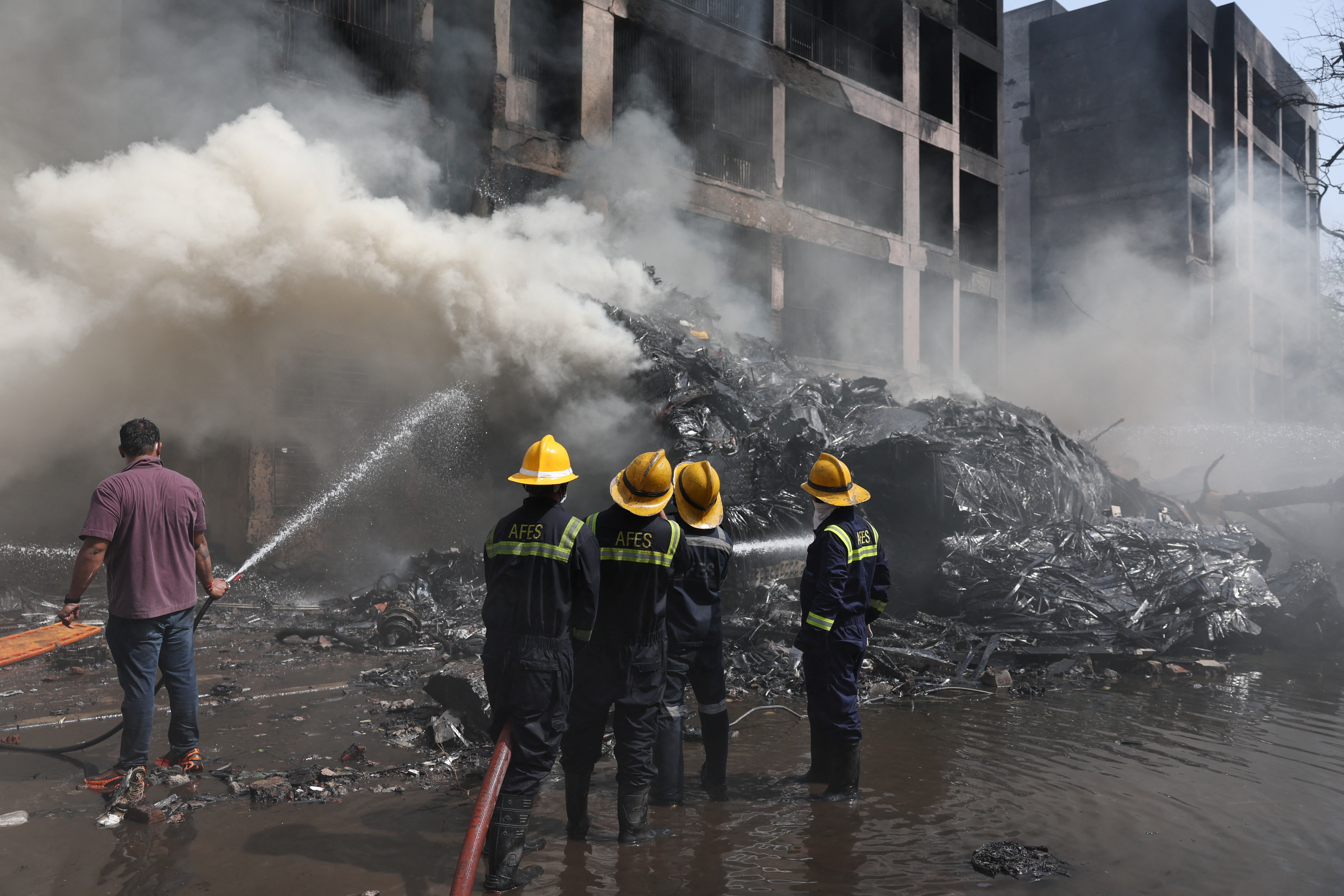 Firefighters work to put out a fire at the site where an Air India plane