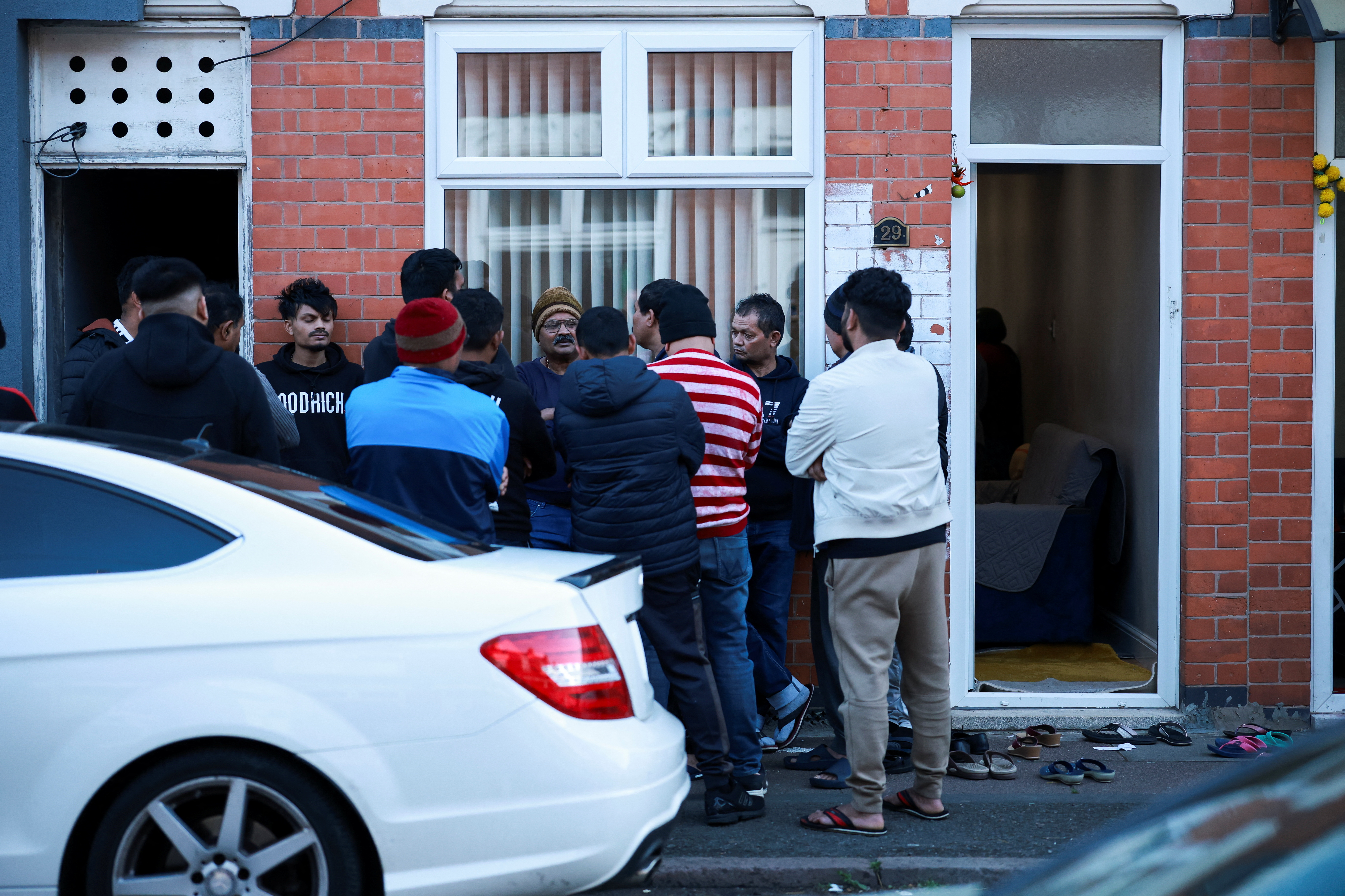 Members of the local community in Leicester, UK, stand outside a home amid news of a deadly Air India crash