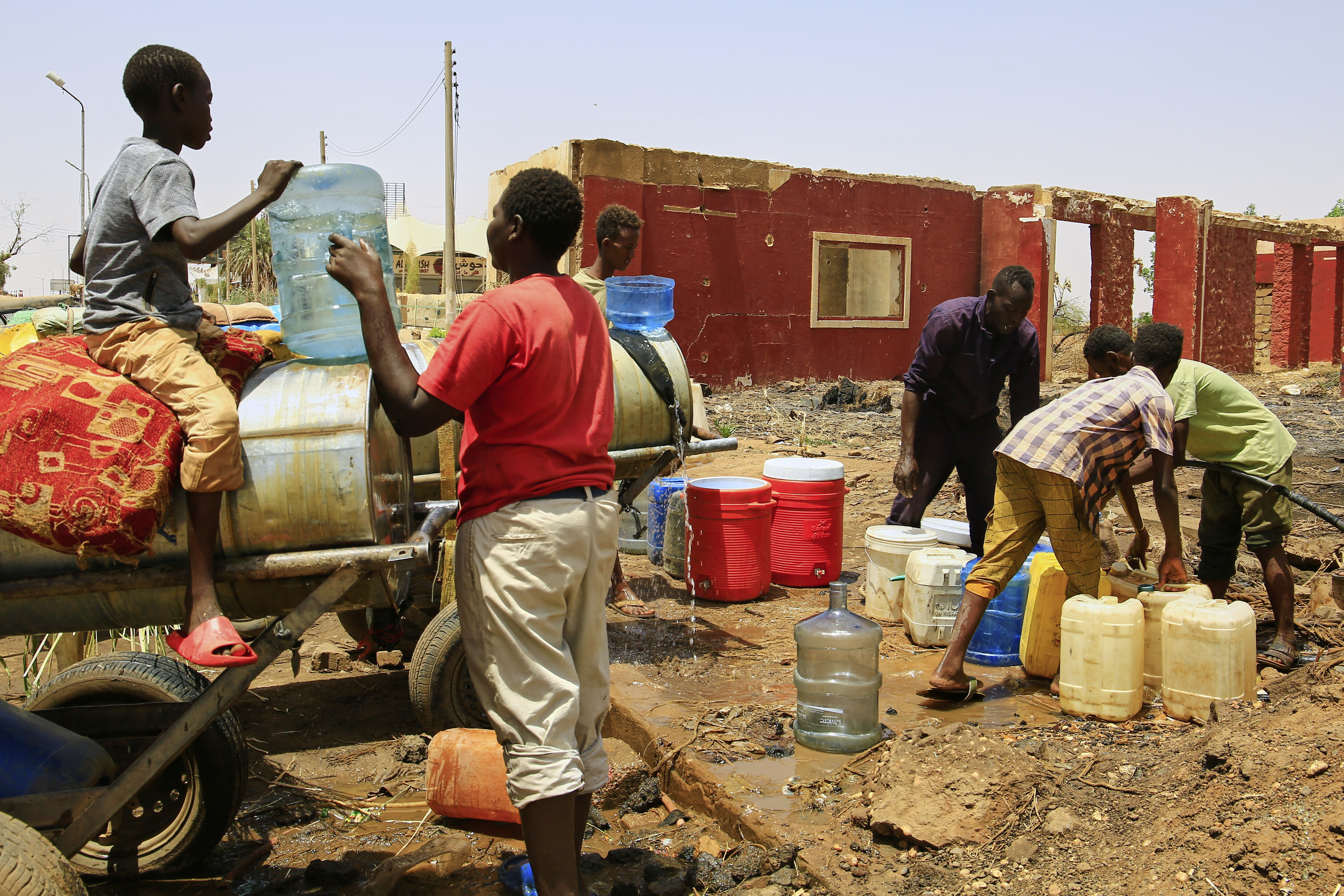 People fill containers by water at a distribution point due to water outages in Khartoum, Sudan, Sunday, May 25, 2025. (AP Photo)