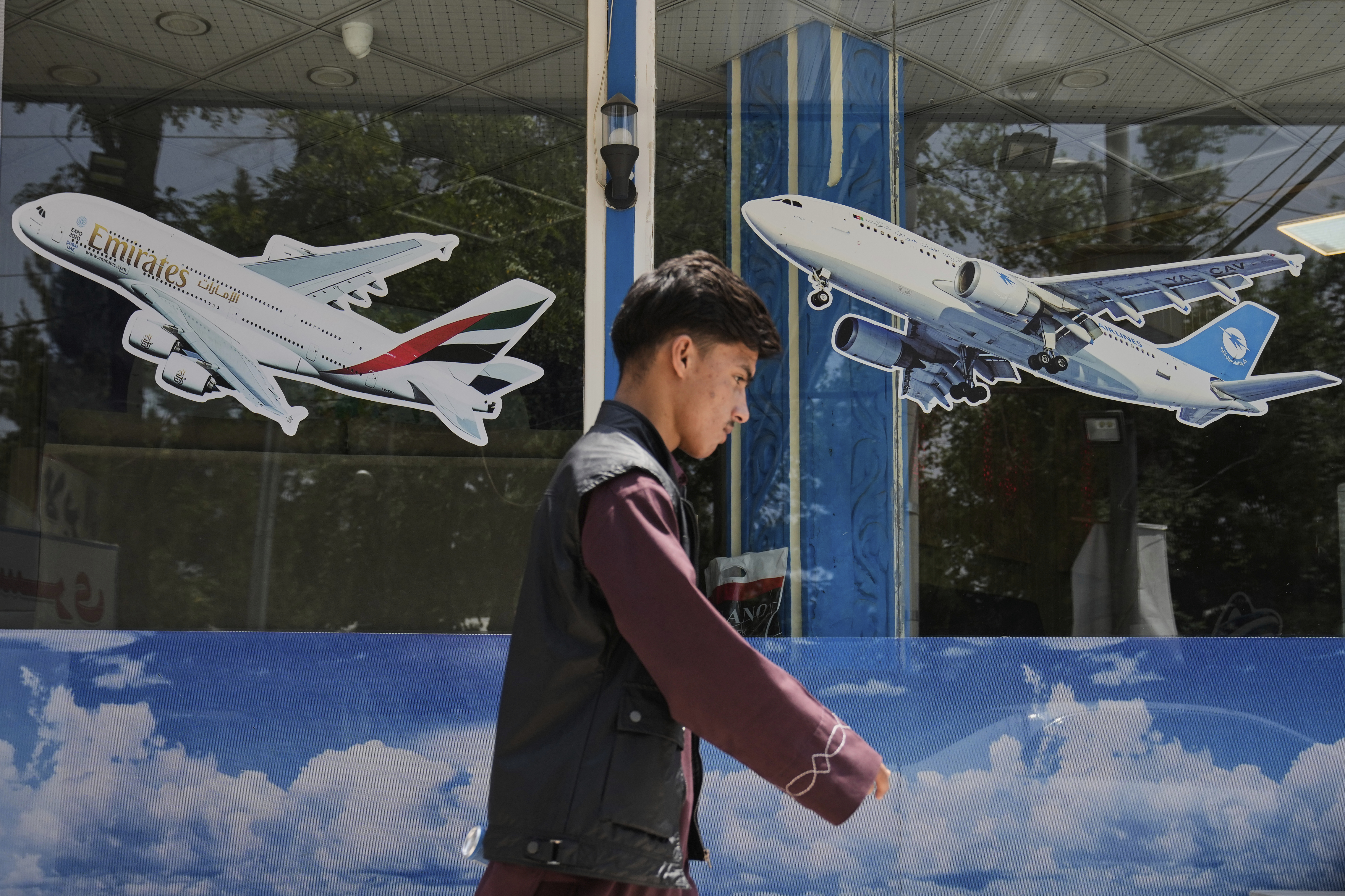 An Afghan man passes in front of an air travel agency.