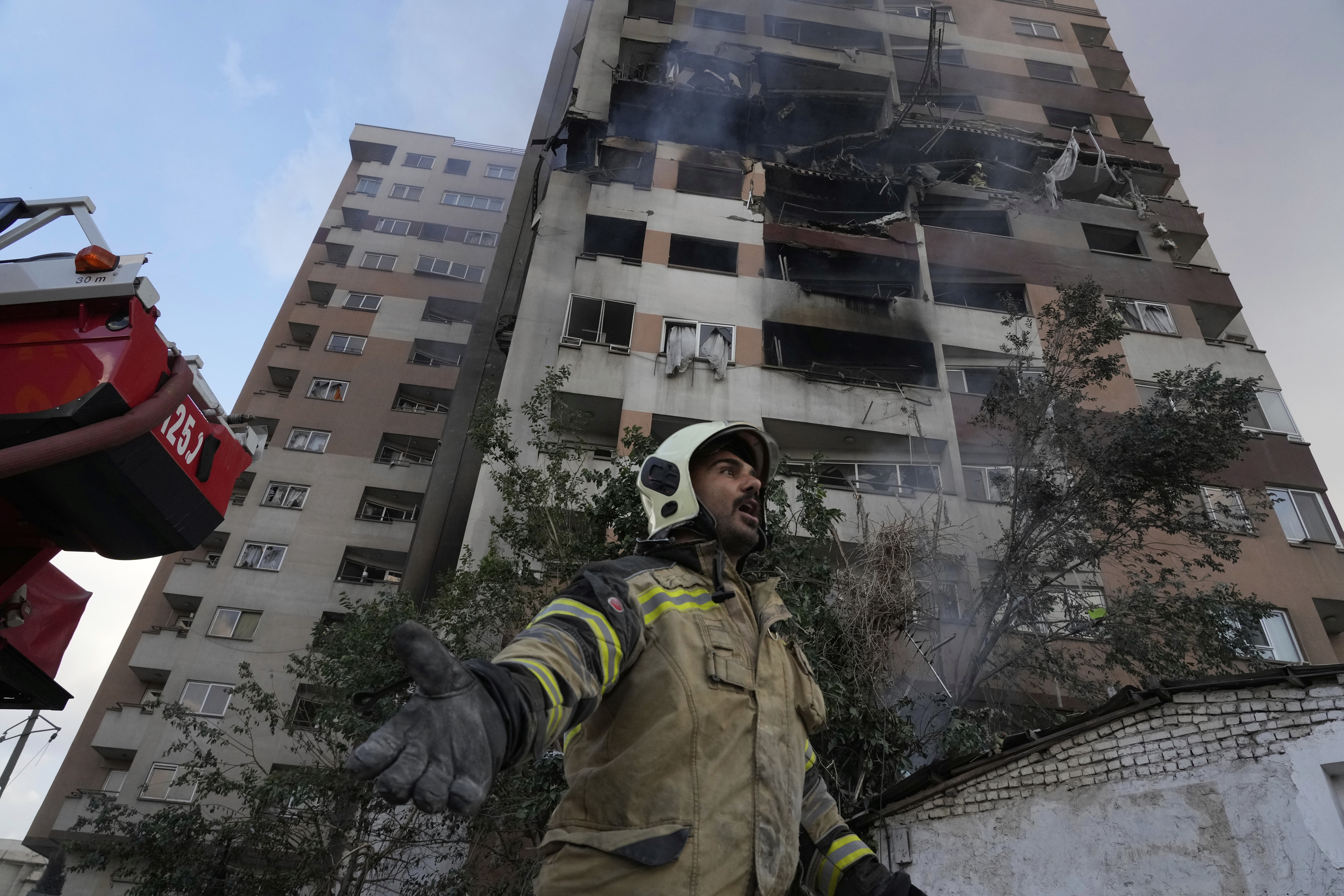 A firefighter calls out his colleagues at the scene of an explosion in a residence compound in northern Tehran