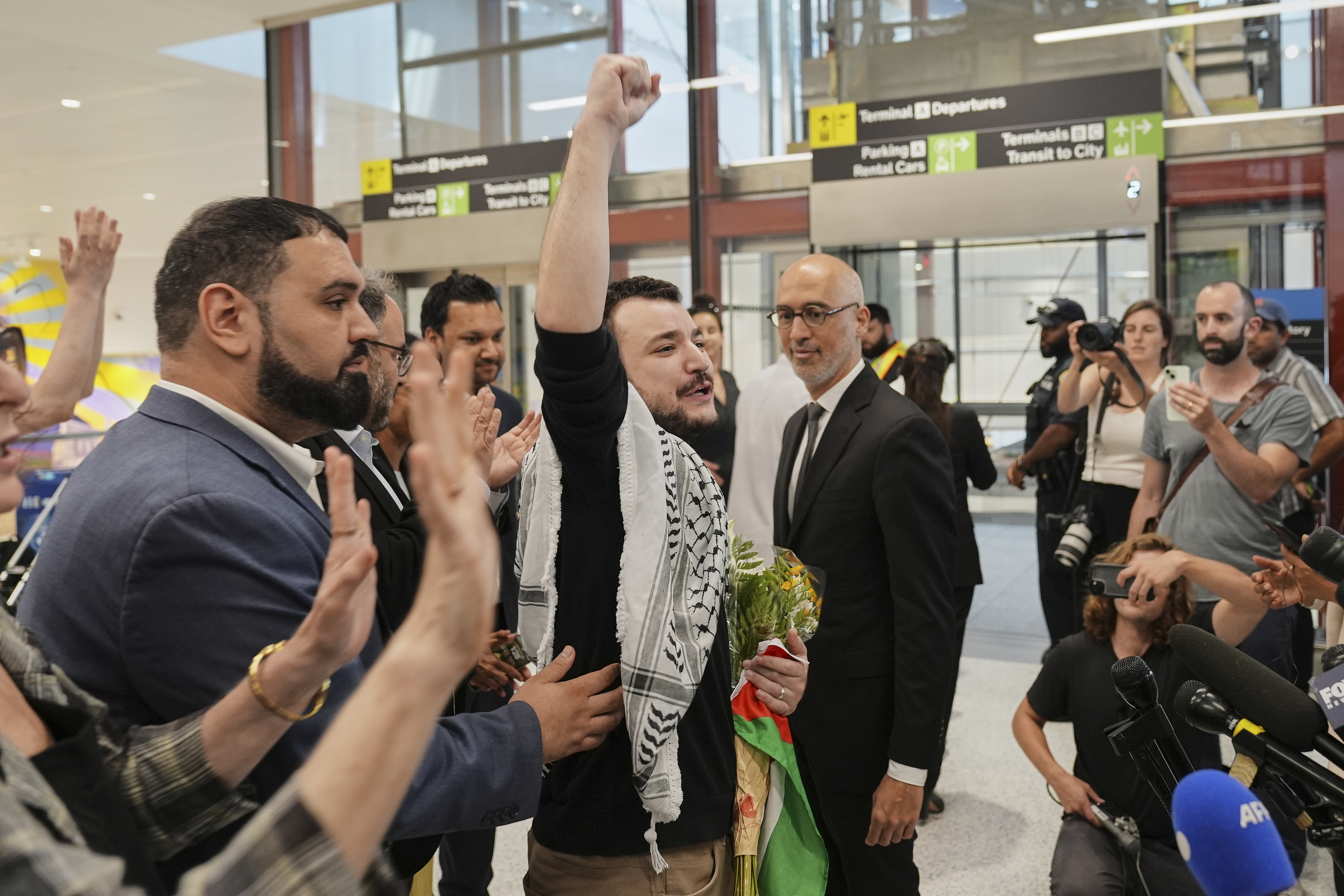 Mahmoud Khalil, center, reacts as he is greeted upon arriving at Newark International Airport,