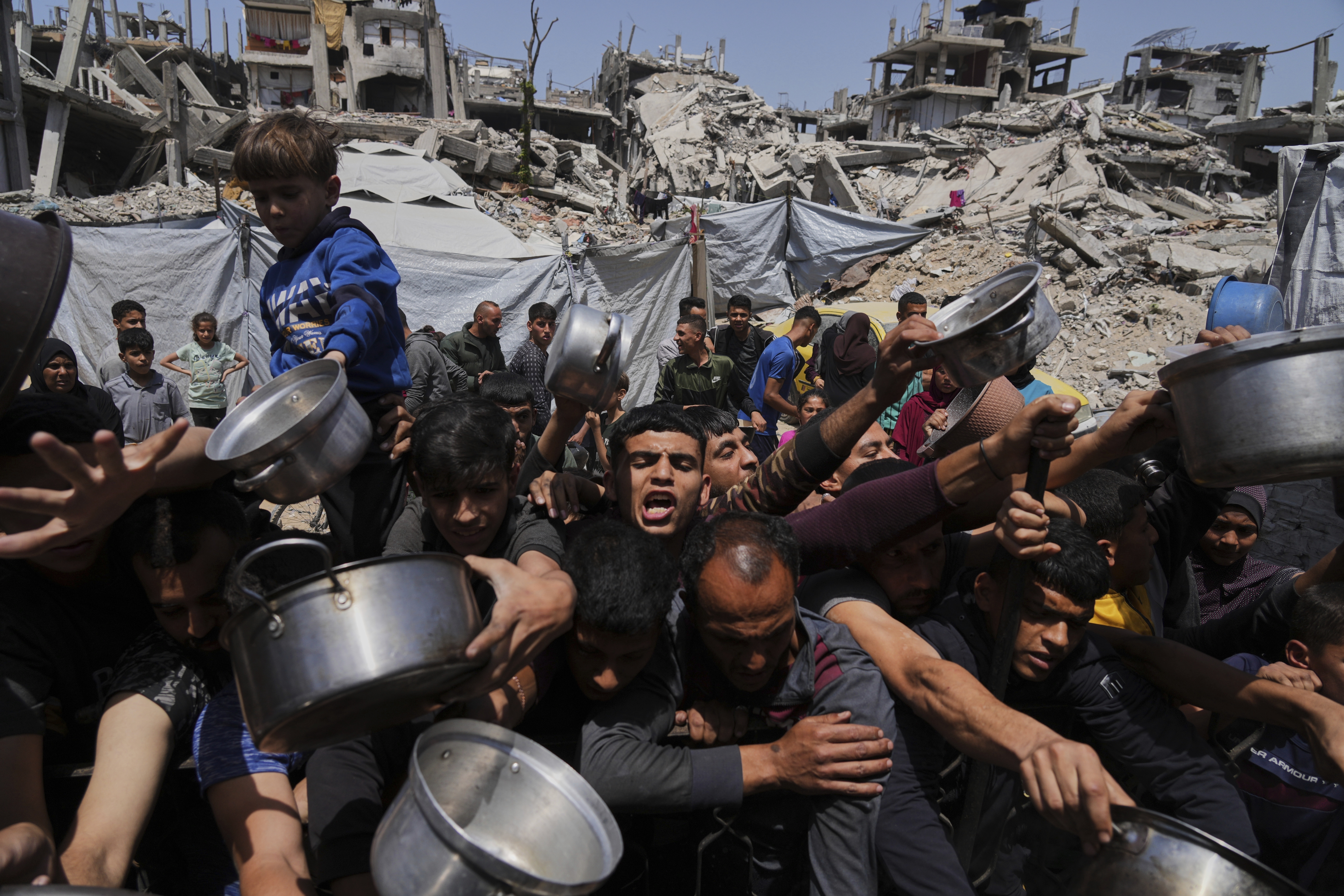 Palestinians struggle to get food at a community kitchen in Beit Lahiya, northern Gaza, in early May [Jehad Alshrafi/AP]