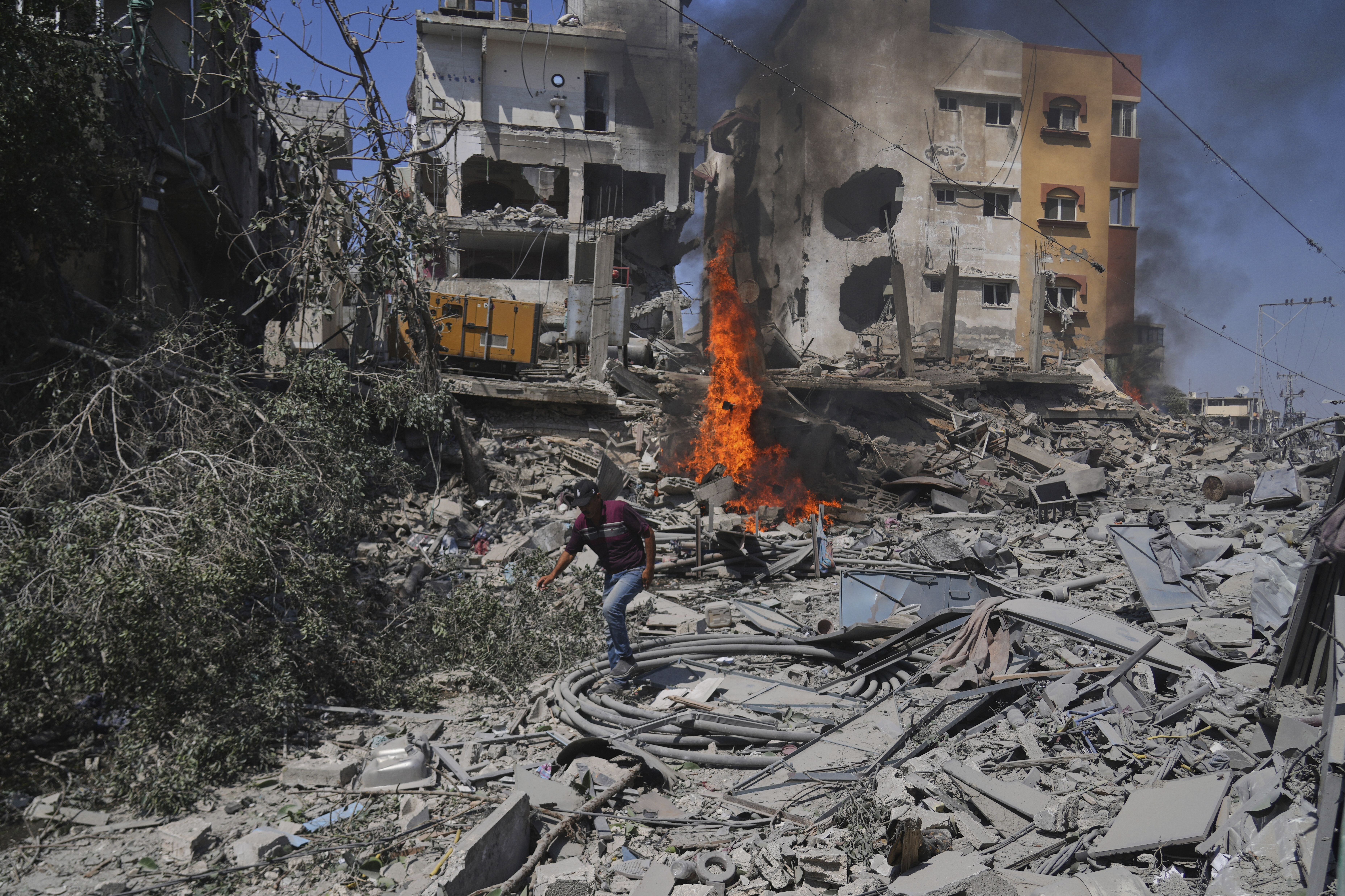 A Palestinian man walks across the rubble of a building destroyed by an Israeli strike in Deir al-Balah, central Gaza Strip, Monday, June 16, 2025. (AP Photo/Abdel Kareem Hana)