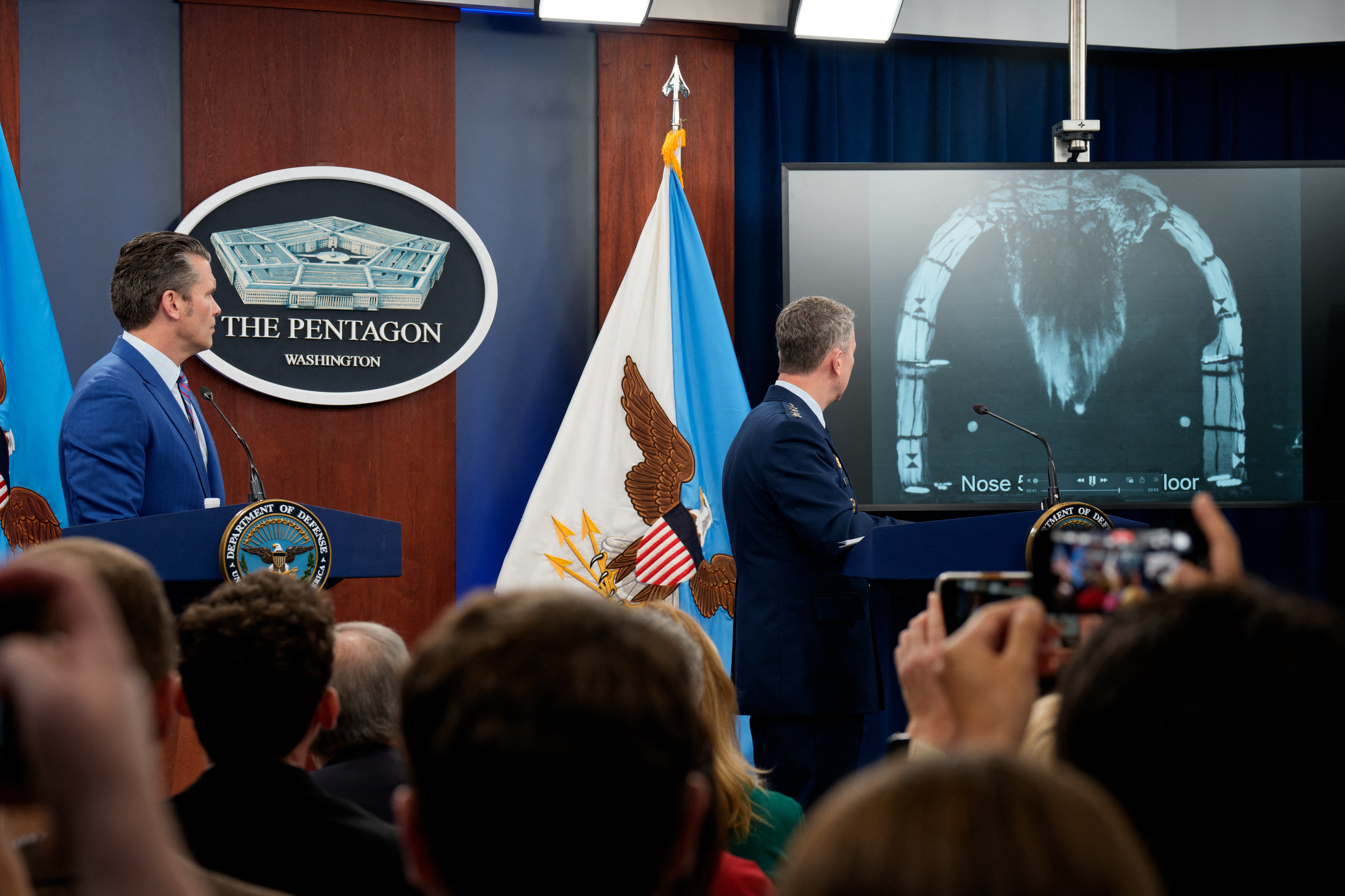 US Defense Secretary Pete Hegseth (L) and Chairman of the Joint Chiefs of Staff Air Force Gen. Dan Caine (R) turn to watch a video of a bombing test of the GBU-57A/B Massive Ordnance Penetrator (MOP) used in the attack on the Iranian Fordow Fuel Enrichment Plant during a news conference at the Pentagon on June 26, 2025 in Arlington, Virginia. [Andrew Harnik/Getty Images via AFP]