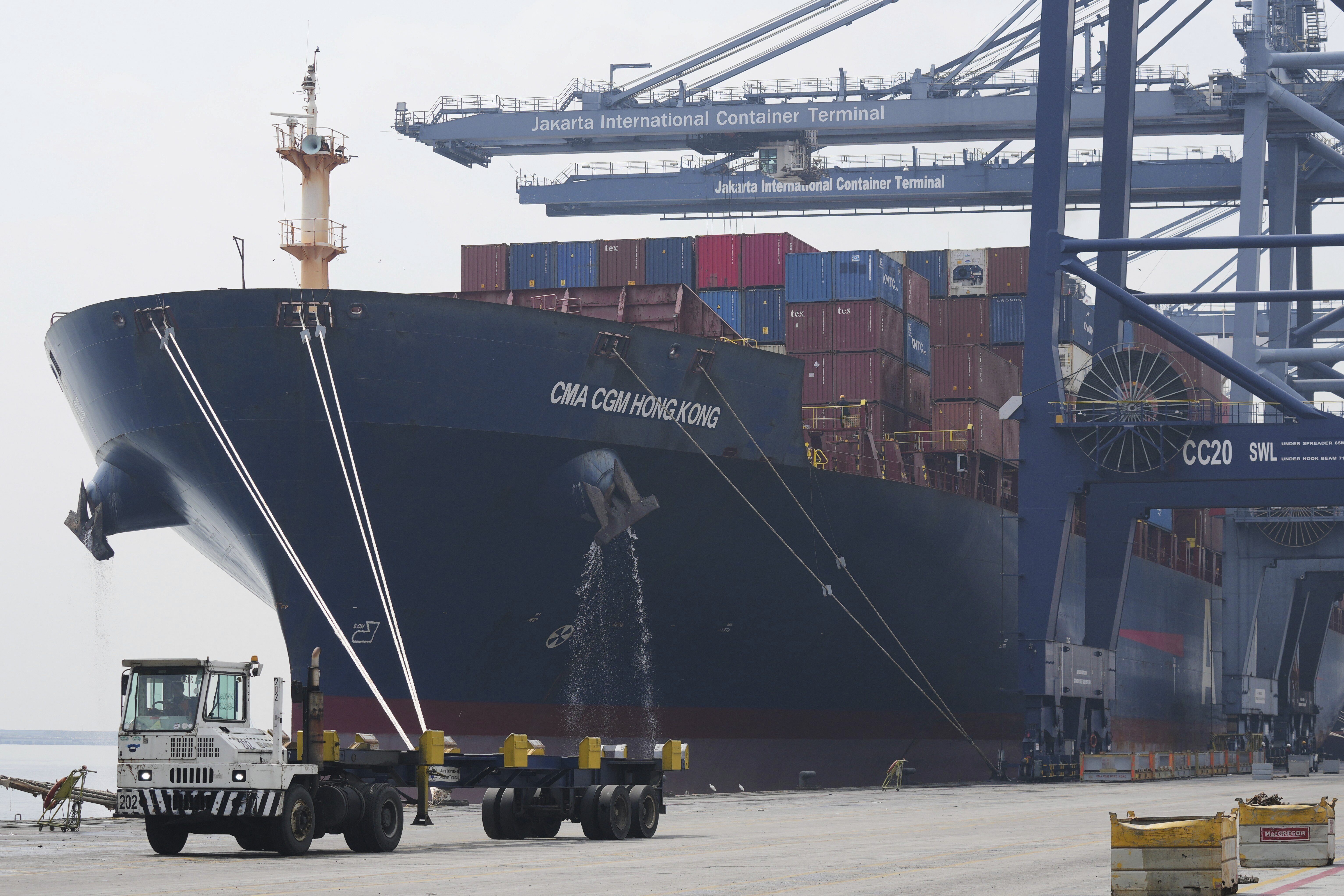 A truck drives past a ship loaded with containers at Jakarta International Container Terminal (JICT) at Tanjung Priok Port in Jakarta, Indonesia, Wednesday, July 9, 2025. (AP Photo/Tatan Syuflana)