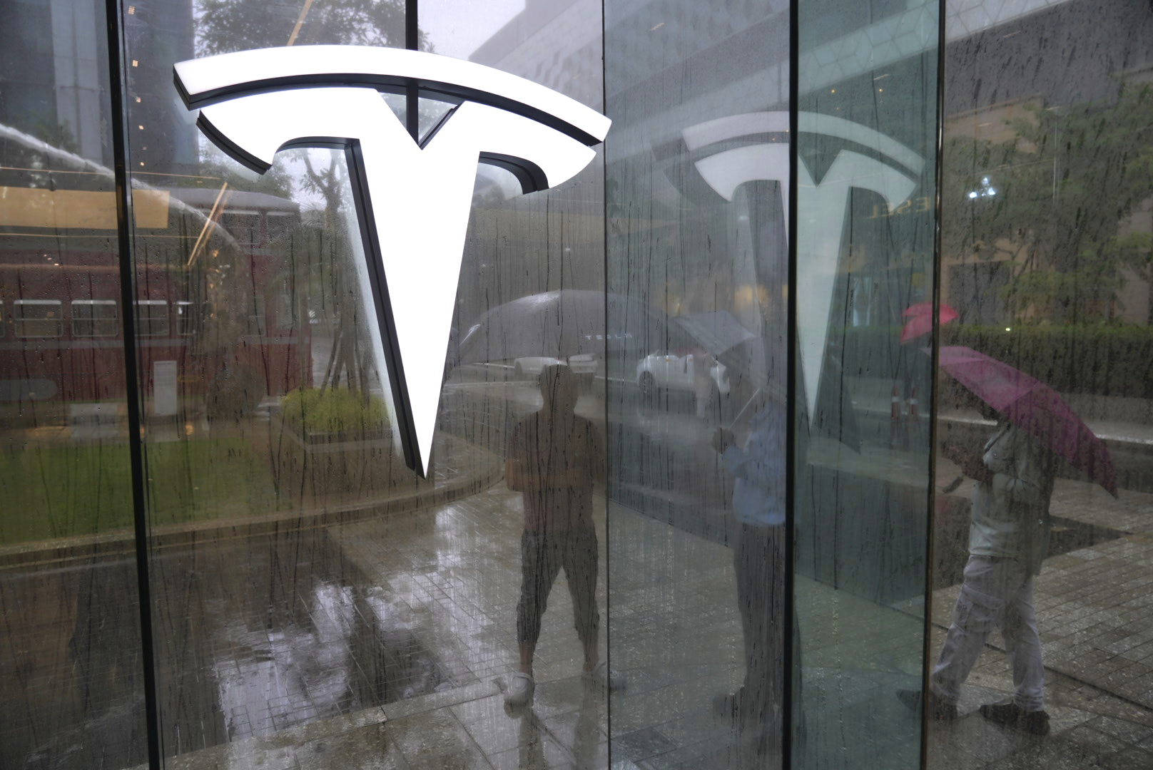 Private security guards stand amidst rain outside India's first Tesla showroom in Mumbai, India, Tuesday, July 15, 2025. (AP Photo/Rafiq Maqbool)