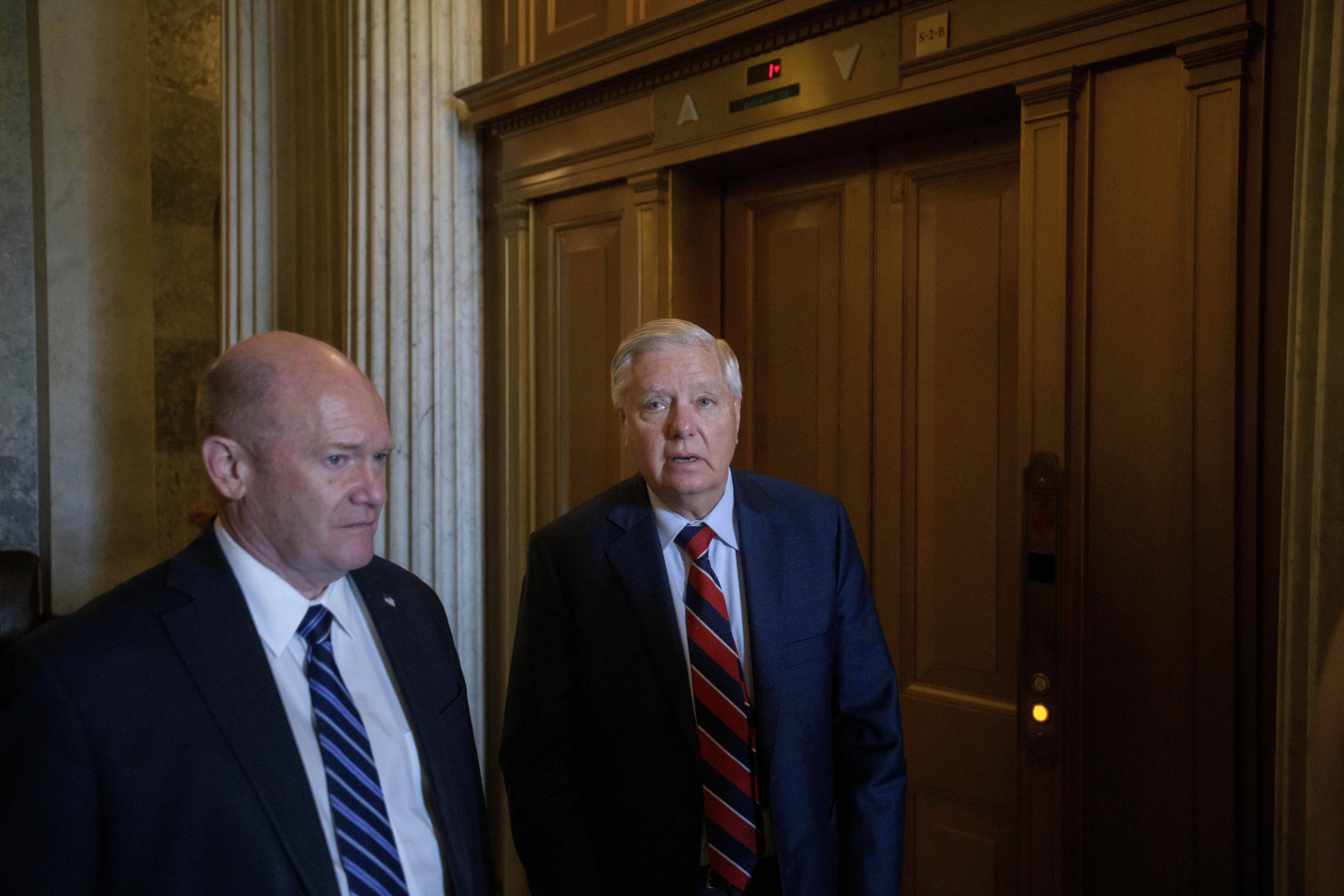 Senator Chris Coons, left, and Senator Lindsey Graham walk from the Senate chamber amid a vote on President Donald Trump's request to cancel about $9 billion in foreign aid and public broadcasting spending