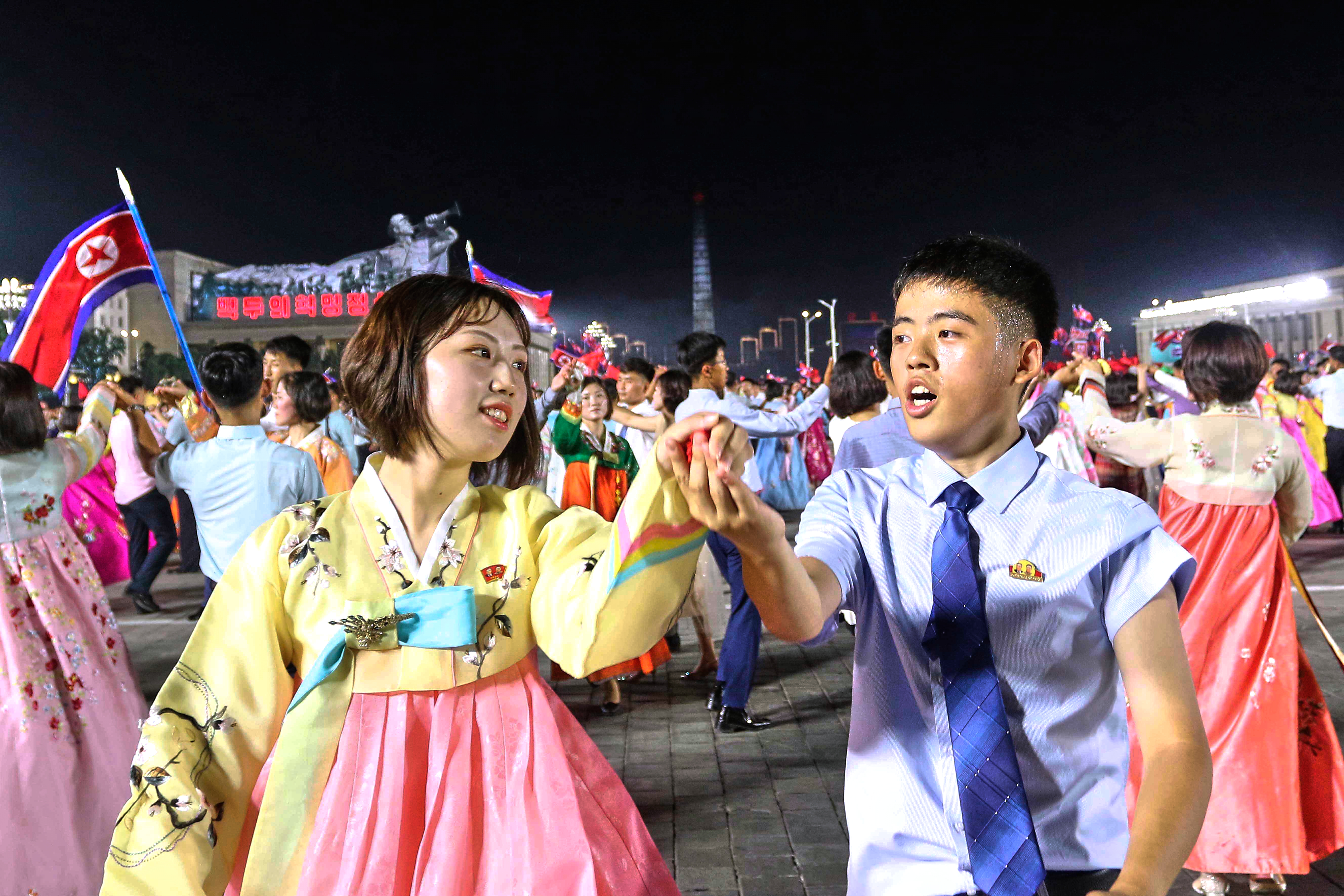 North Korean youth and students dance during an evening gala with a firework display to celebrate the 72nd anniversary of the armistice of the Korean War