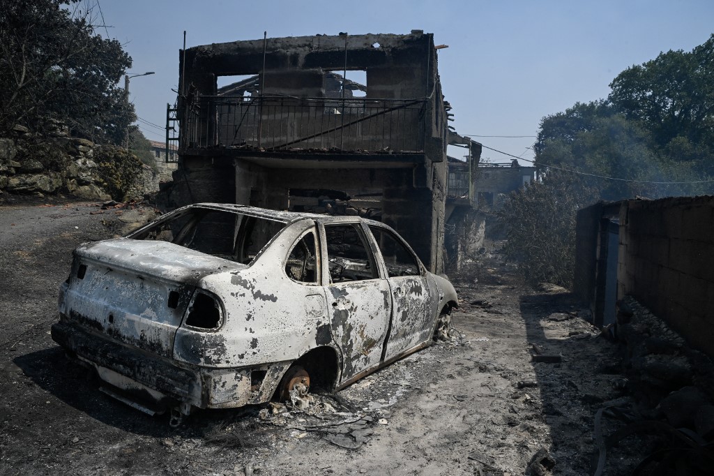 A burnt houses and car are seen after a wildfire in Caridade, near Monterrei in the province of Ourense, northern Spain on August 14, 2025. [Miguel Riopa/ AFP]