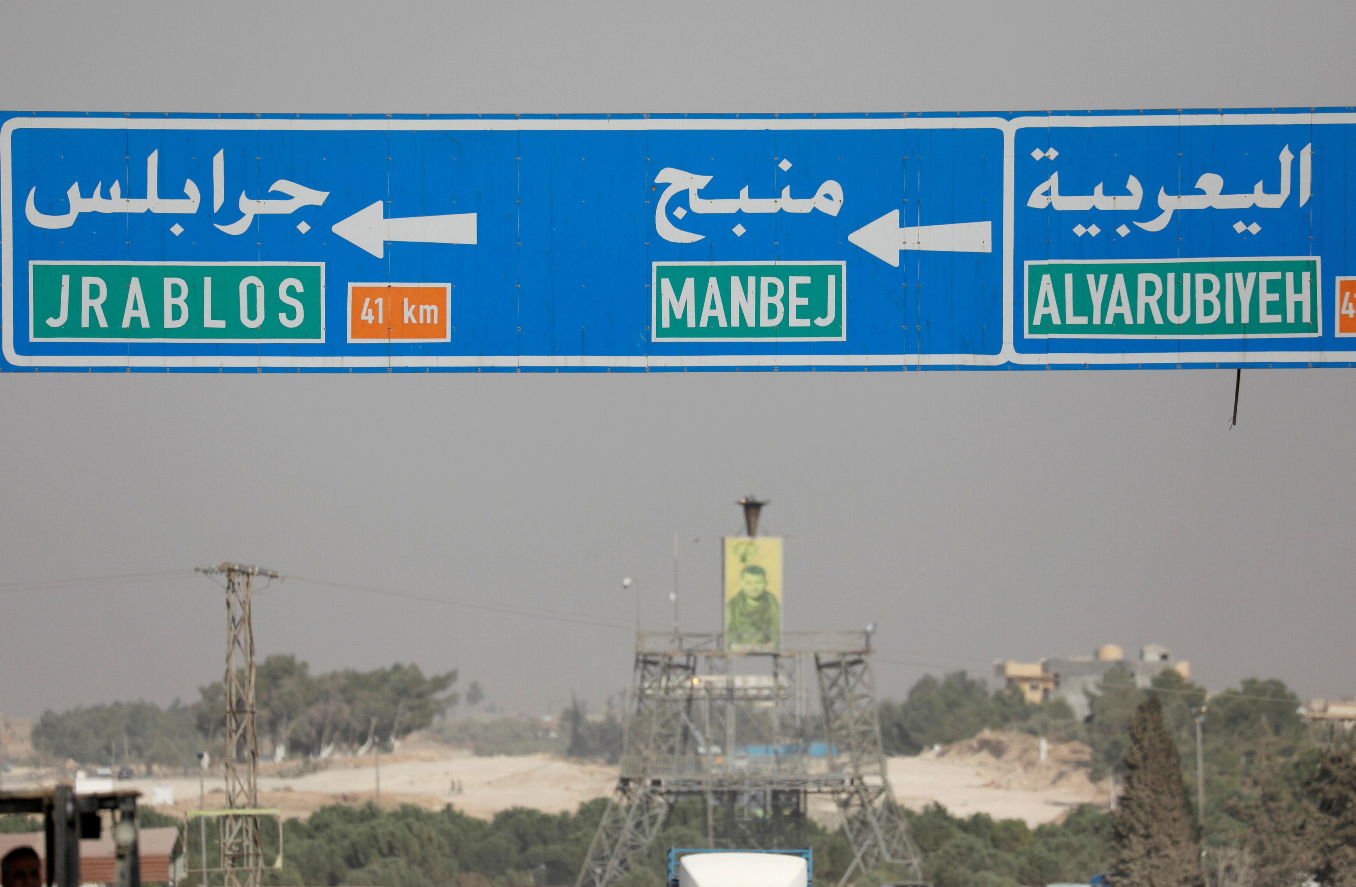 A road sign shows the direction to the city of Manbij in northern Syria