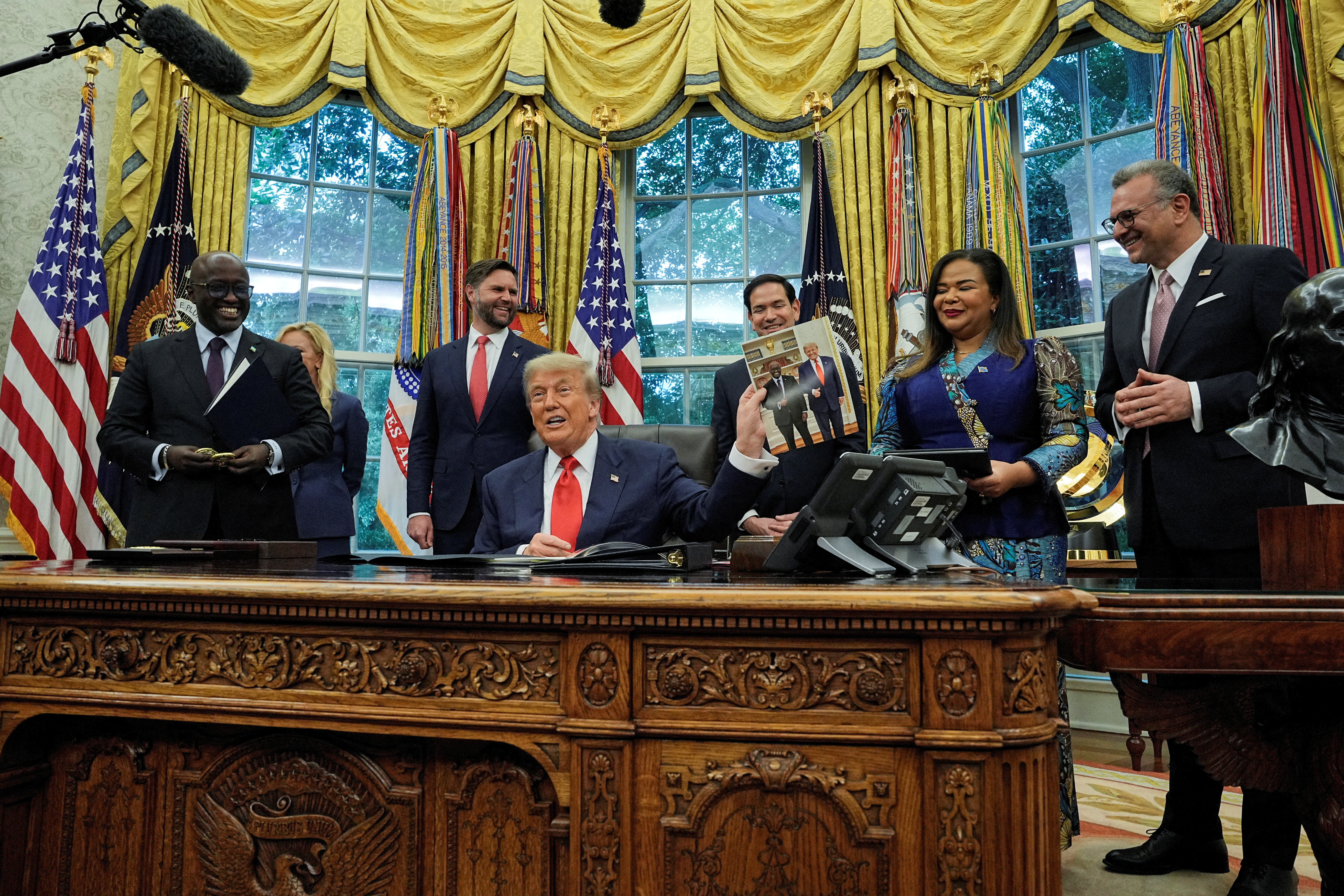 Trump sits at the Resolute Desk, surrounded by representatives from the DRC and Rwanda.