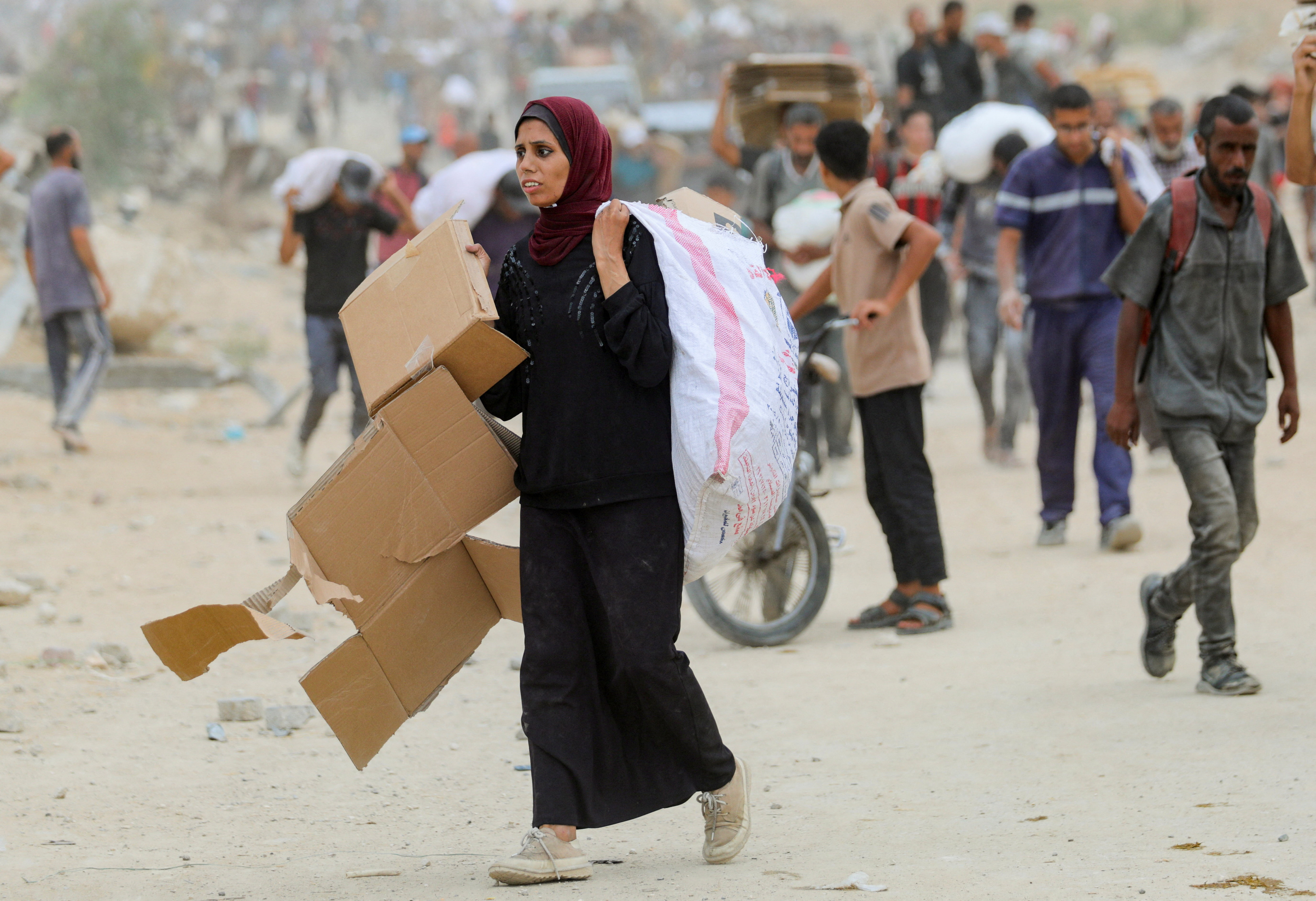 A woman carries empty cardboard boxes as Palestinians receive aid supplies from the U.S.-backed Gaza Humanitarian Foundation (GHF), in the central Gaza Strip, August 1, 2025. REUTERS/Stringer