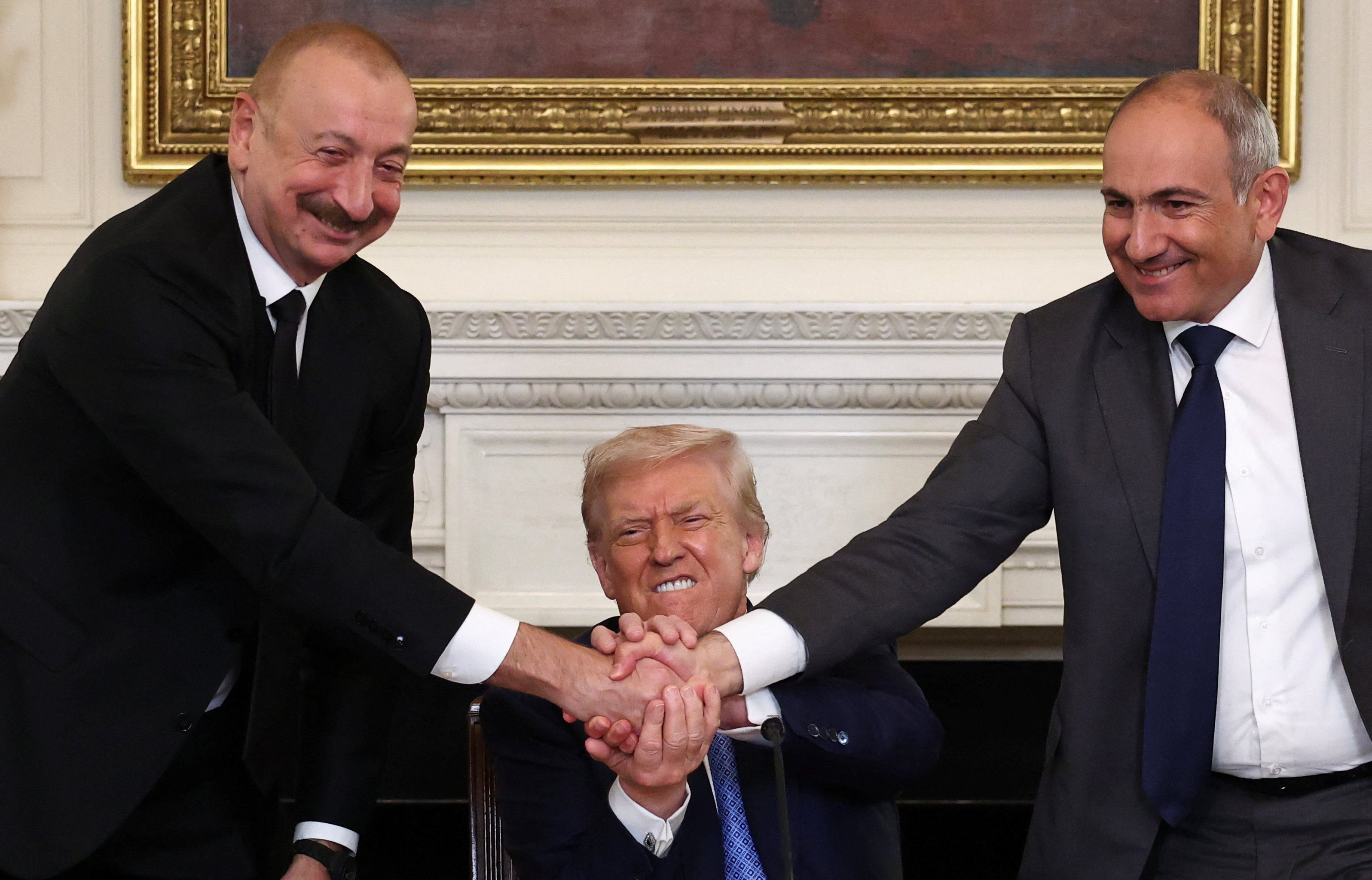 U.S. President Donald Trump holds the hands of Azerbaijan's President Ilham Aliyev and Armenia's Prime Minister Nikol Pashinyan as they shake hands between each other during a trilateral signing event