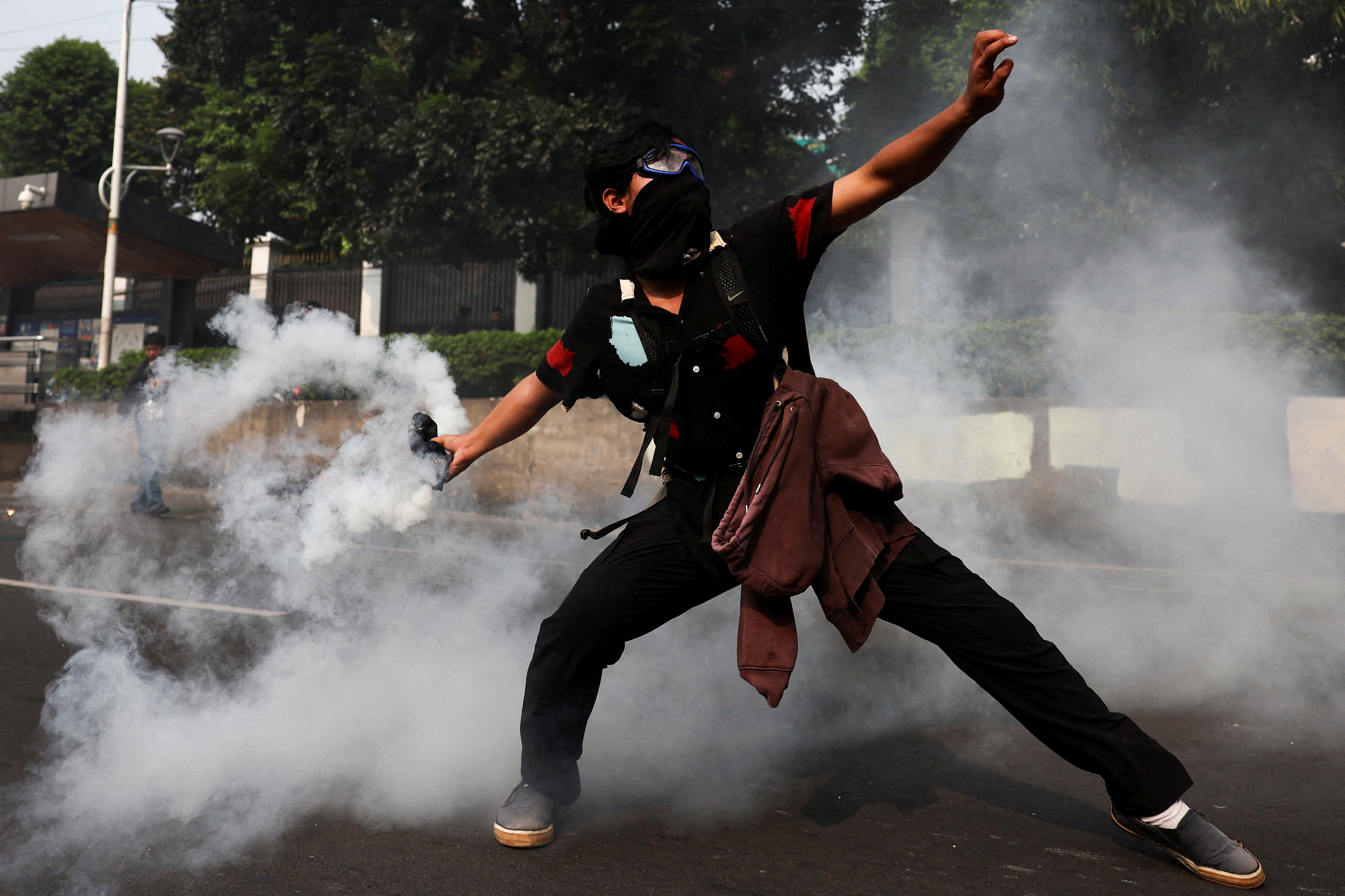 A man attempts to throw back a tear gas canister toward riot police during a protest against what the demosntrators say, are exorbitant allowances for Indonesian parliament members, outside Indonesian parliament buildings in Jakarta, Indonesia, August 25, 2025.
