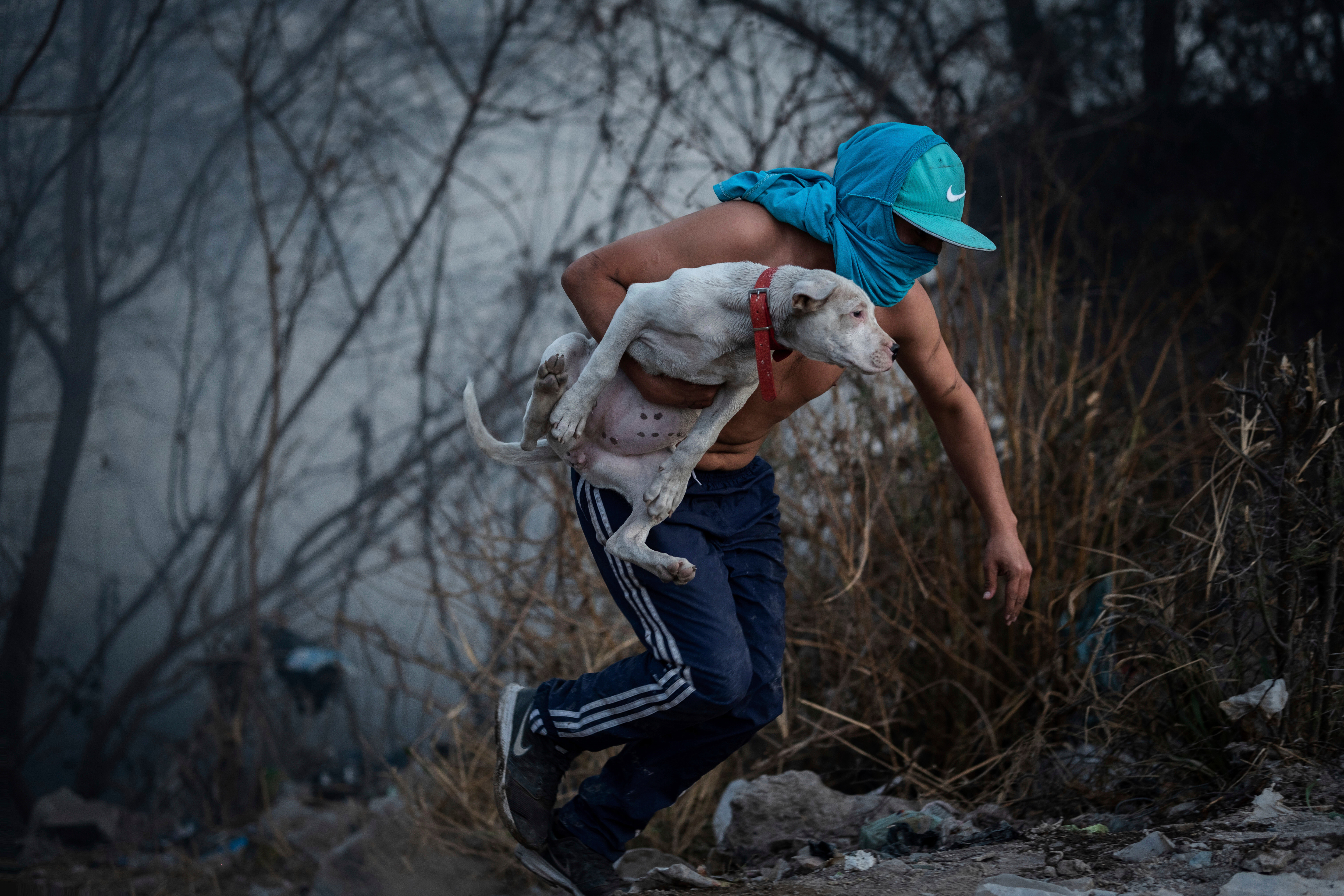 A man, holding a dog, runs from a blaze raging through a neighborhood of Salta, Argentina