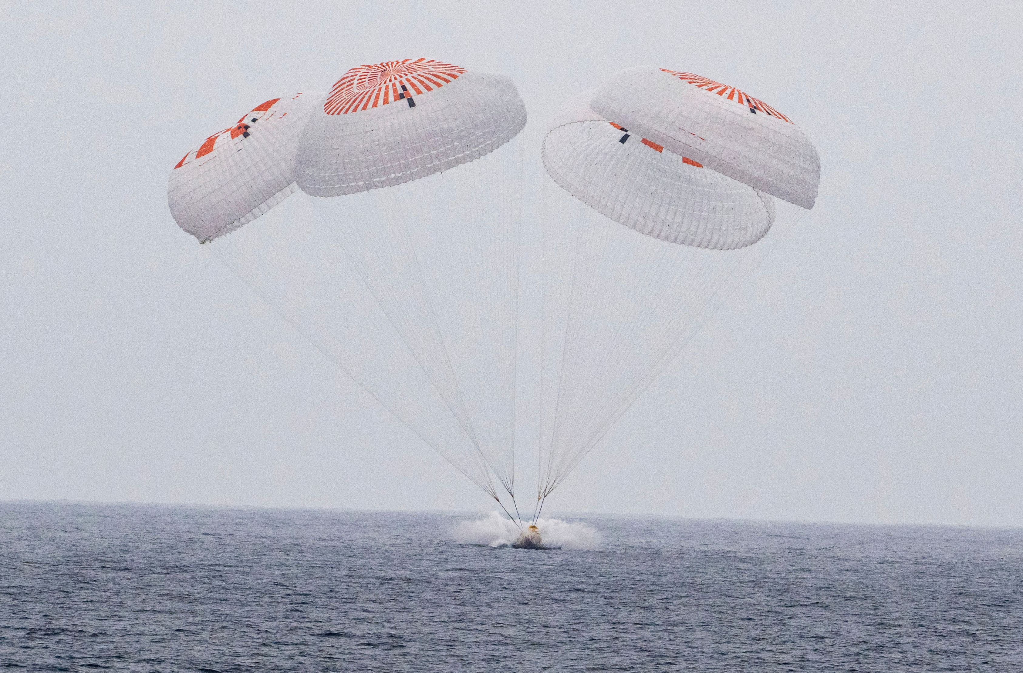 SpaceX capsule parachutes into the ocean.