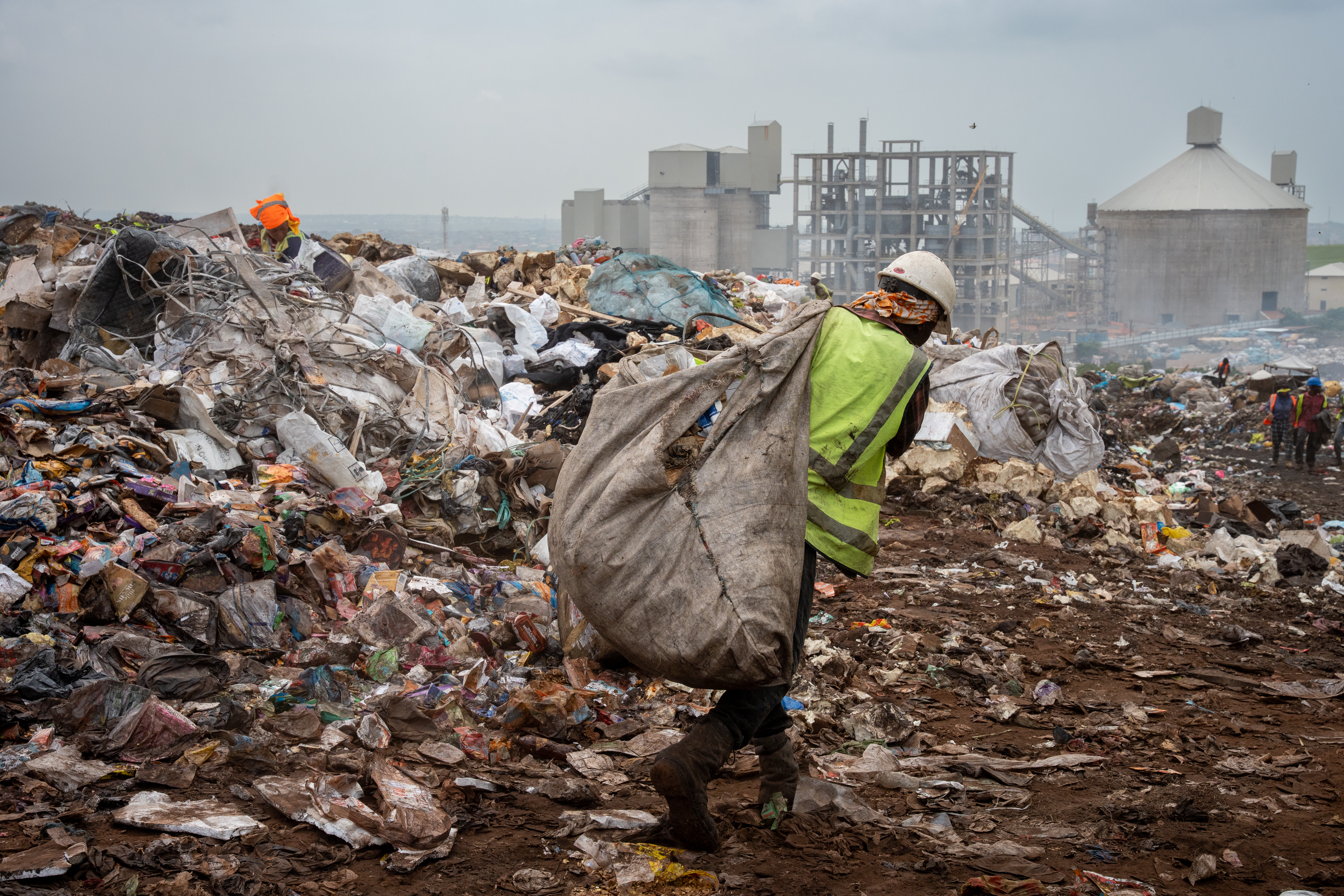 A waste picker worker moves recyclable waste from a landfill.
