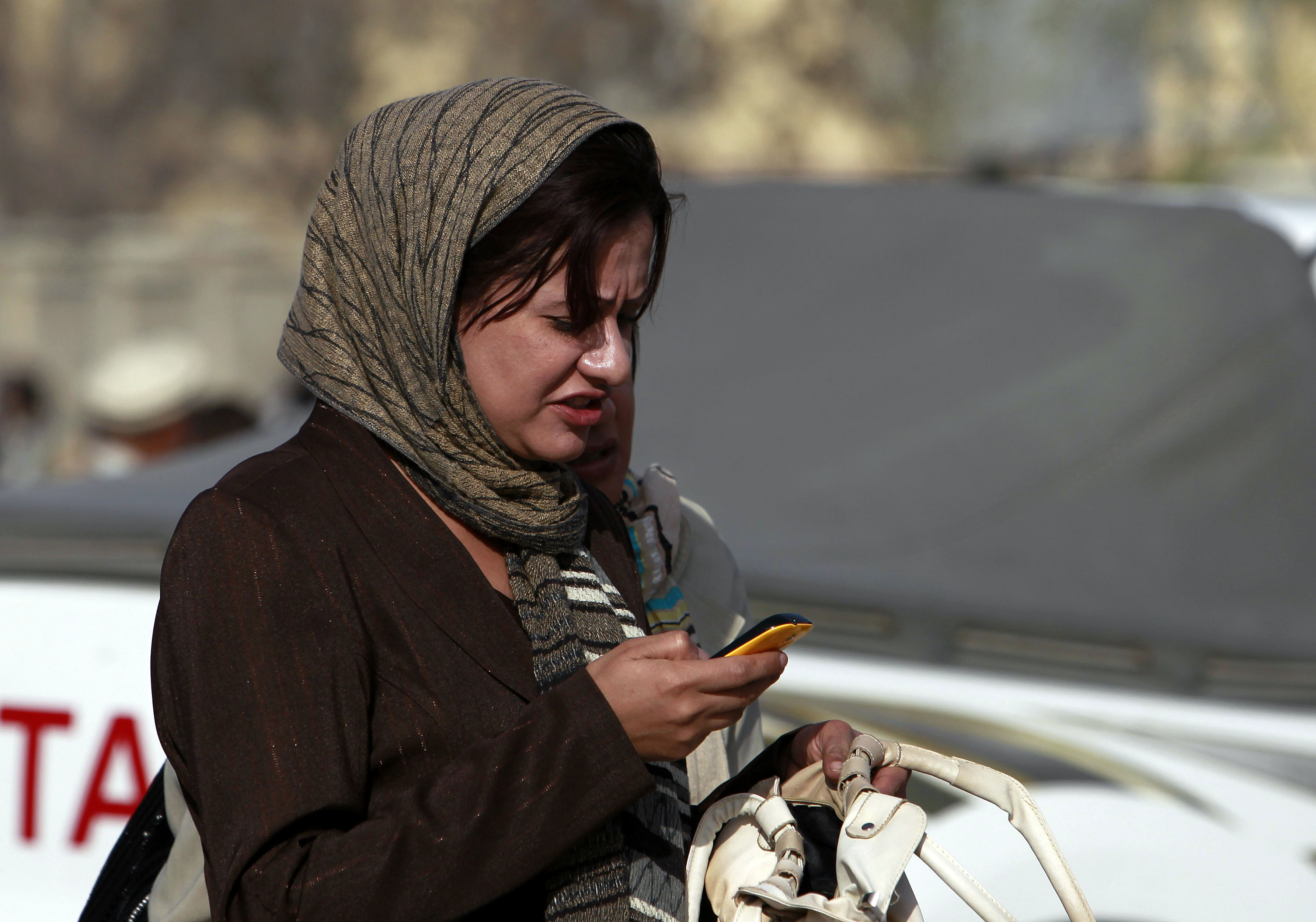 An Afghan woman looks at her mobile phone on a street in Kabul.