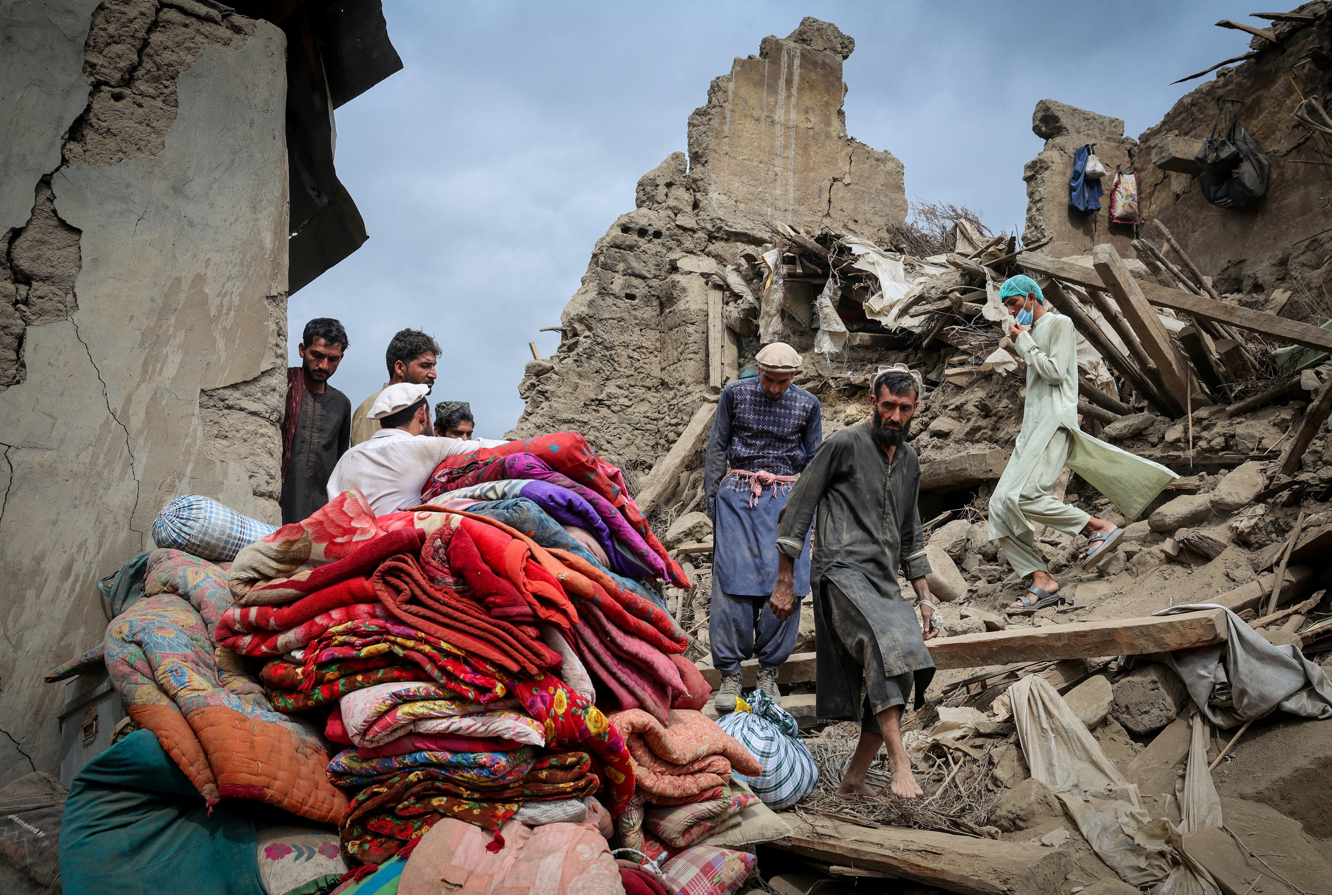 Afghan men walk on the rubble of a damaged house following a deadly magnitude-6 earthquake that struck Mazar Dara, in Kunar province, Afghanistan on September 2, 2025.