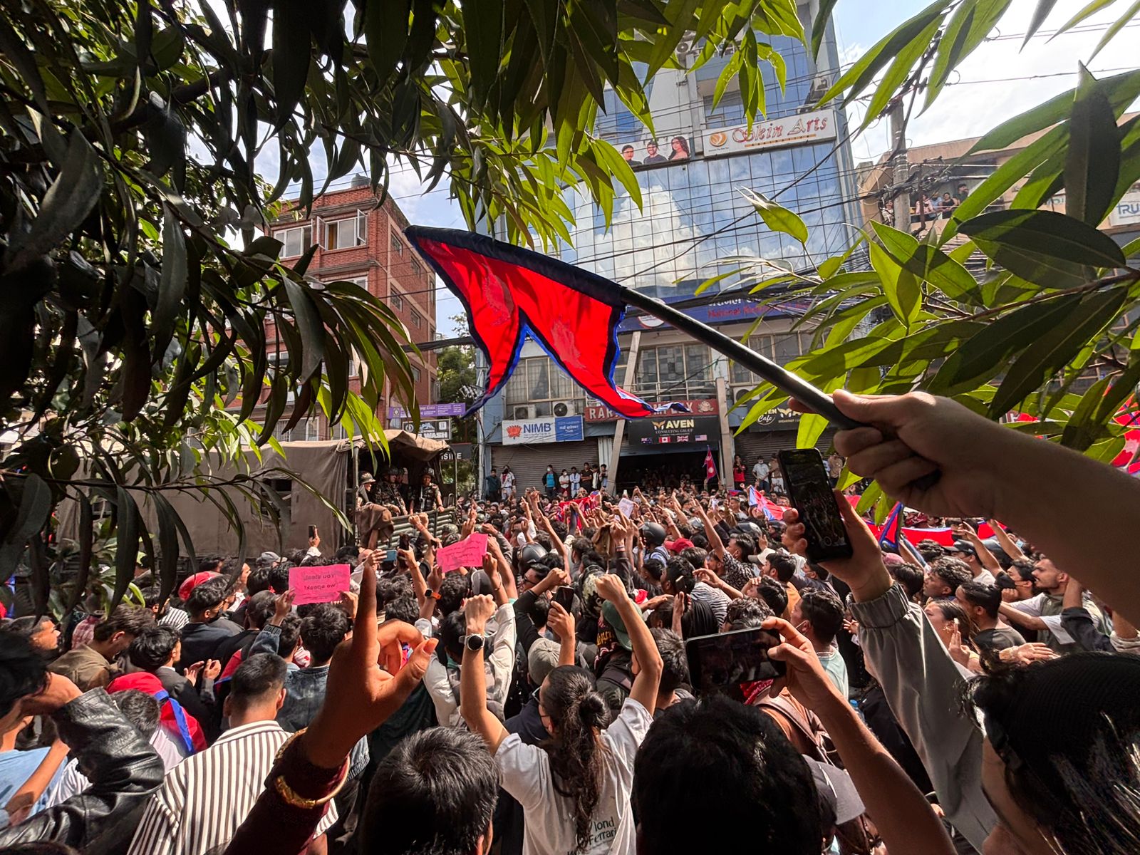 Protesters on a Kathmandu street waving the national flag and chanting slogans on Monday [Samik Kharel/Al Jazeera]