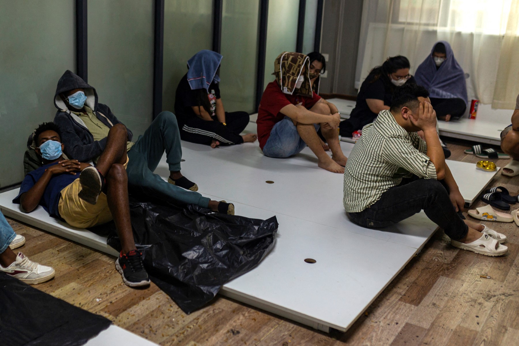 Alleged scam centre workers and victims rest during a crackdown operation by the Karen Border Guard Force on illicit activity in Shwe Kokko in Myanmar's eastern Myawaddy township in February. [AFP]