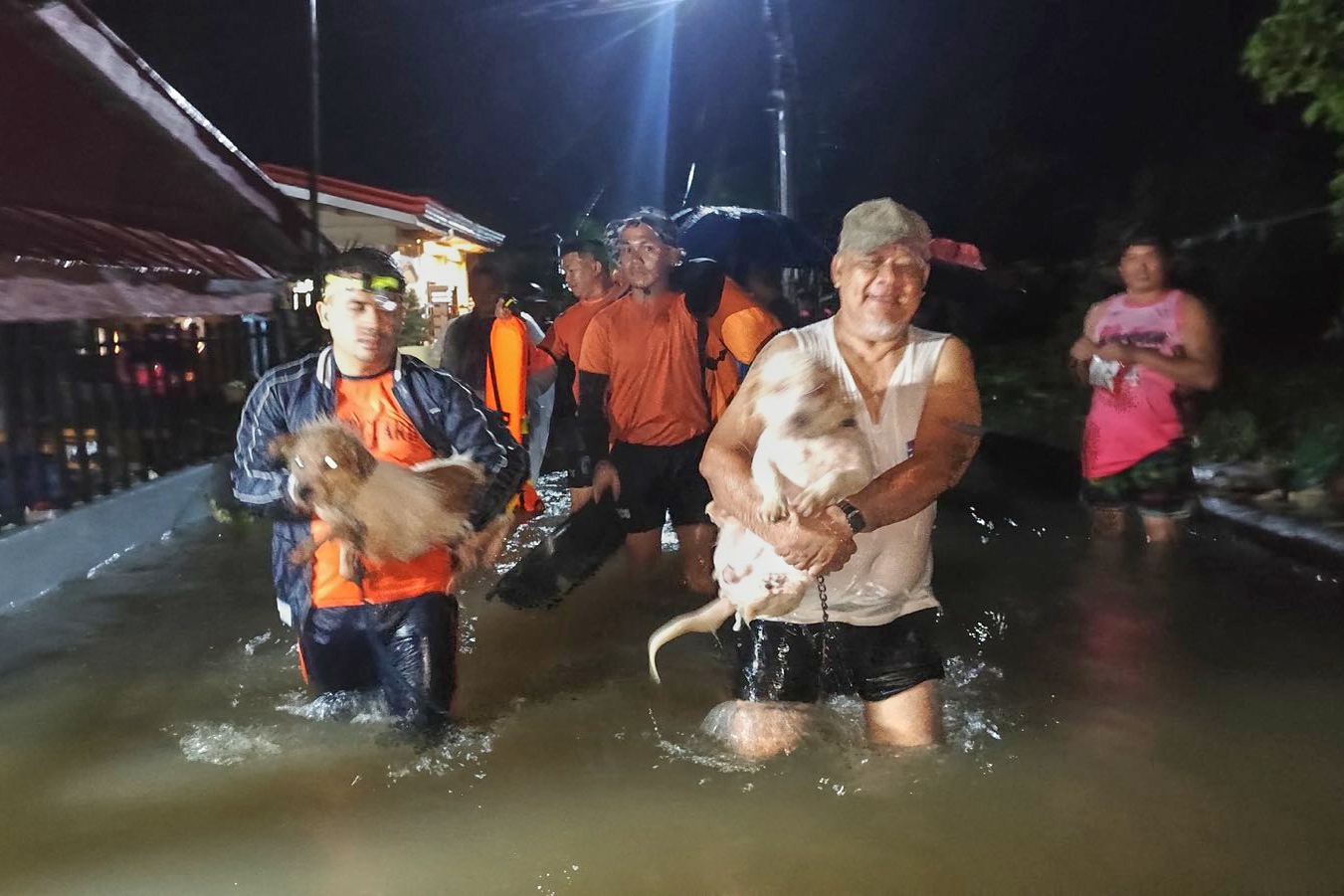 Residents and their dogs are evacuated by rescuers.