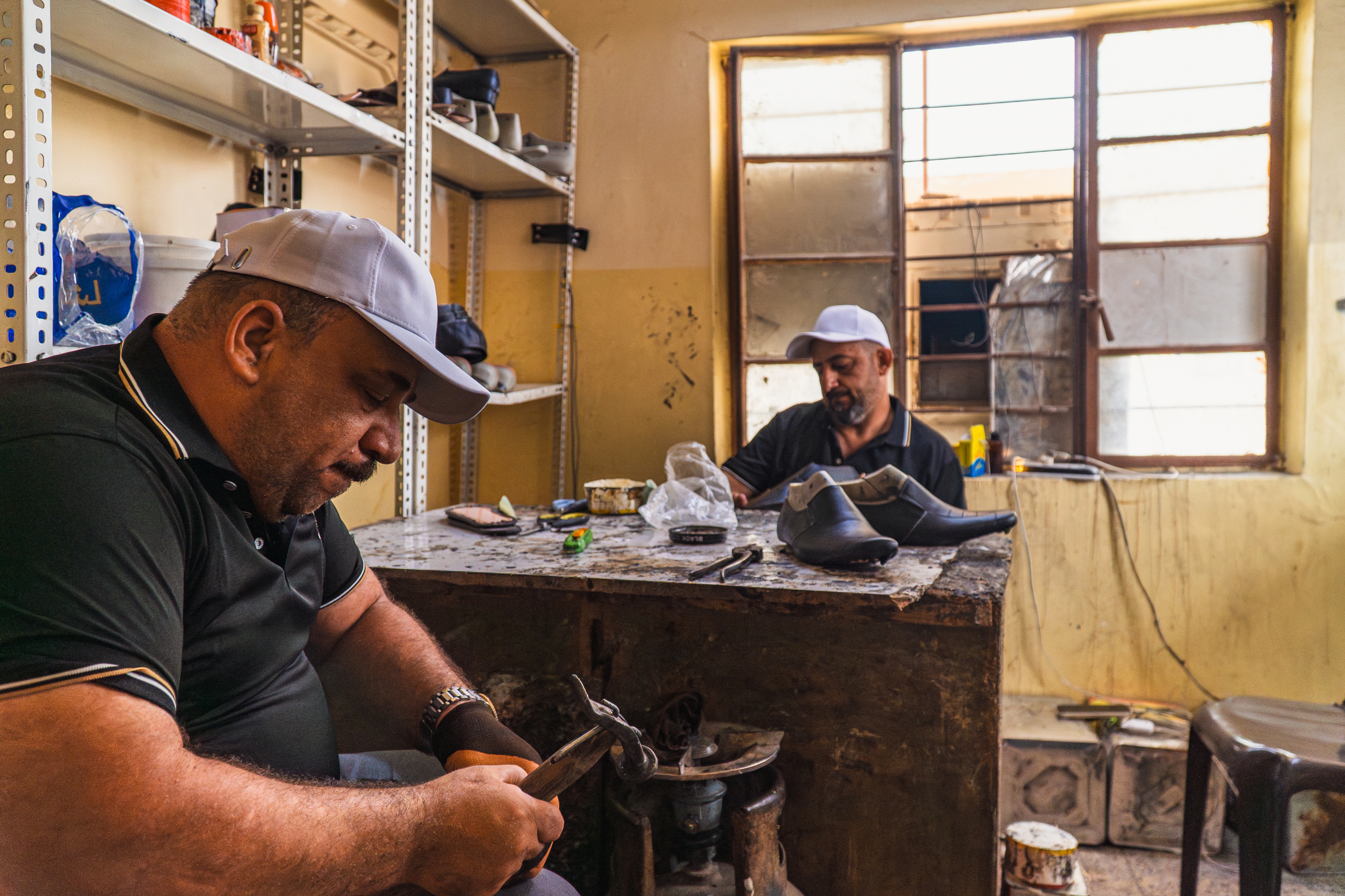 A shoemaker in Mosul puts the finishing touches on a leather shoe before it reaches the showroom. Photo: IOM 2025/Aram Hakim