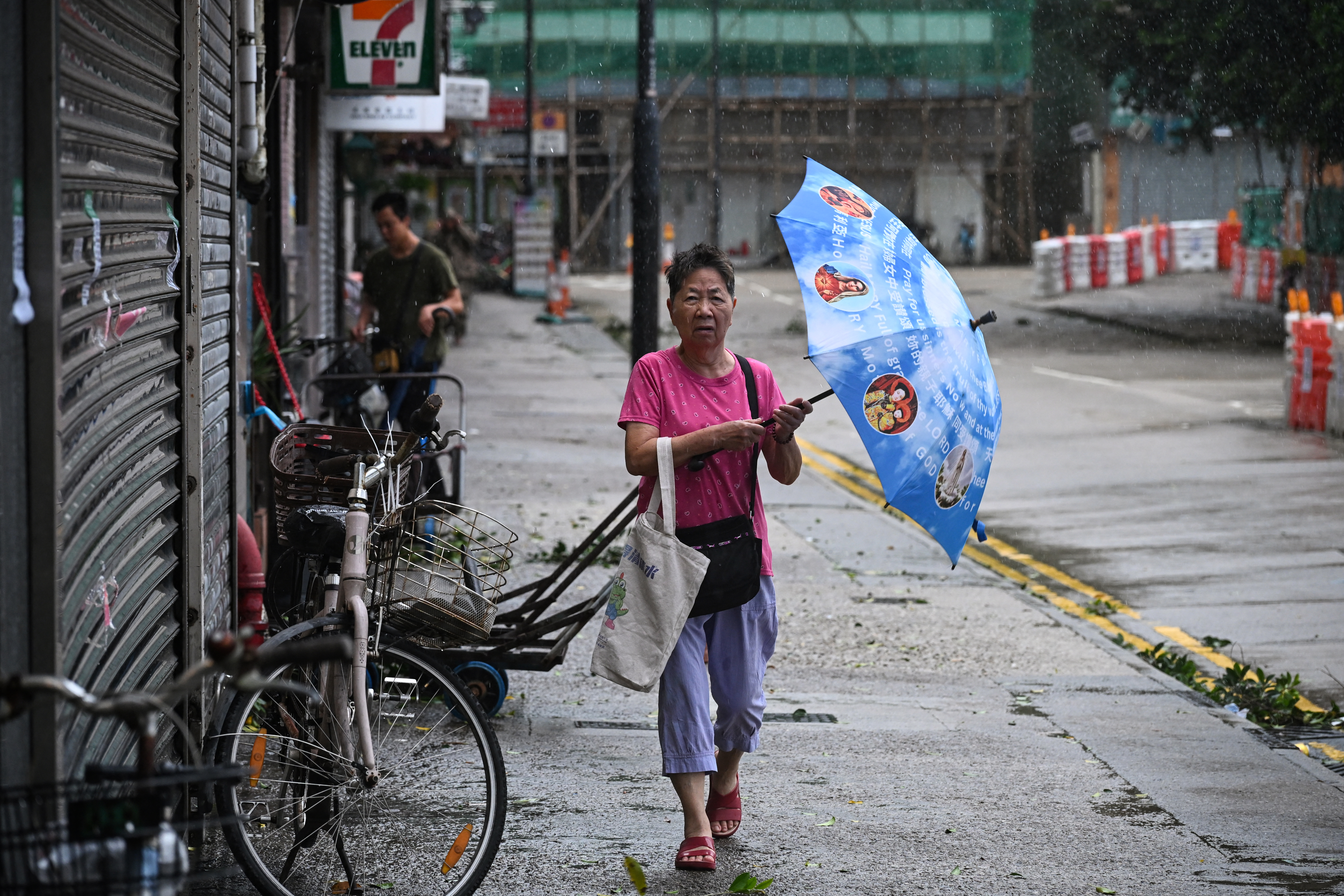 A woman holds her umbrella against the strong winds as she walks along a street as Typhoon signal No. 8 remains in force as Typhoon Tapah heads to coast near Hong Kong on September 8, 2025. [Peter Parks/ AFP]