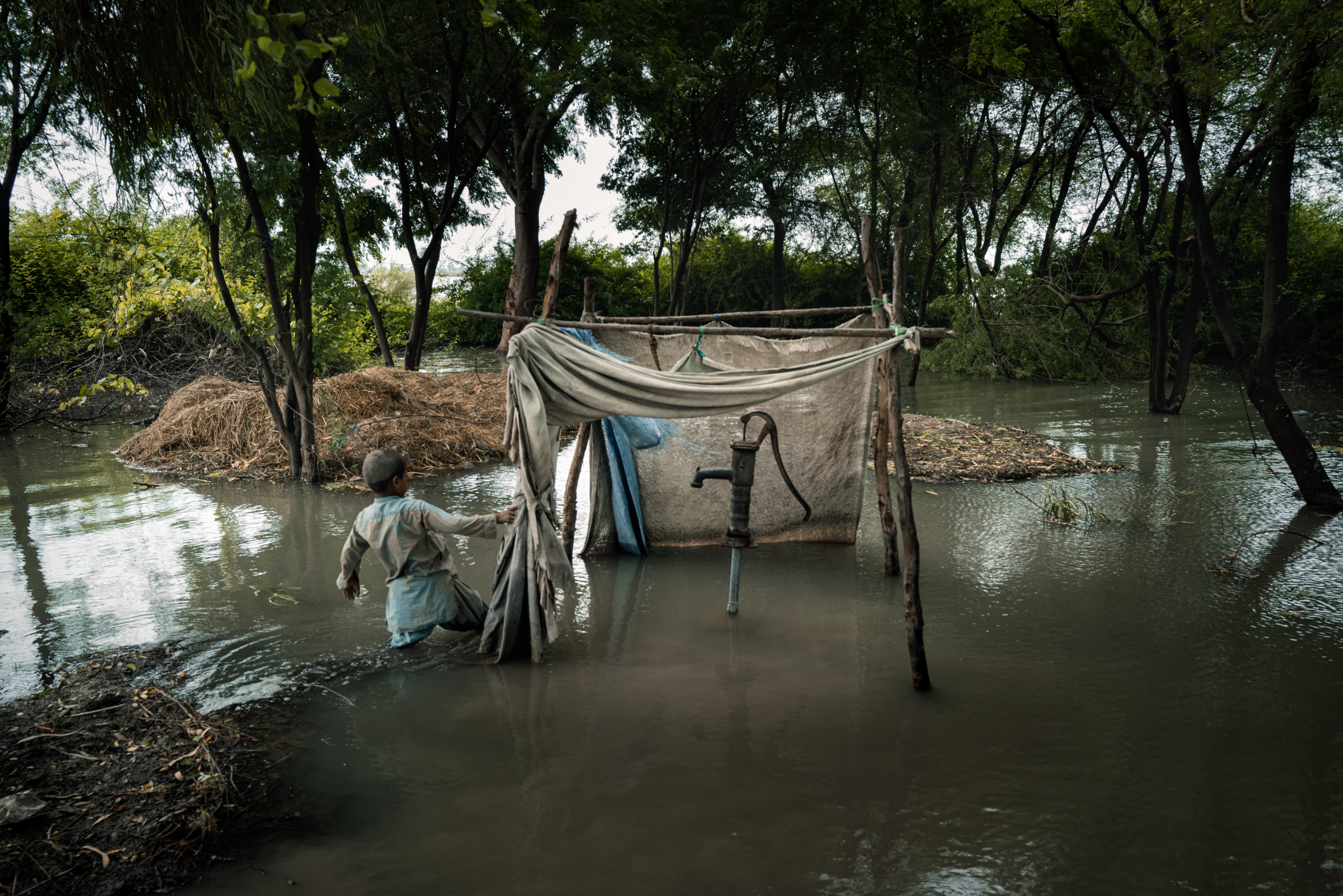 A family’s water pump is submerged by floods at the back of their house.