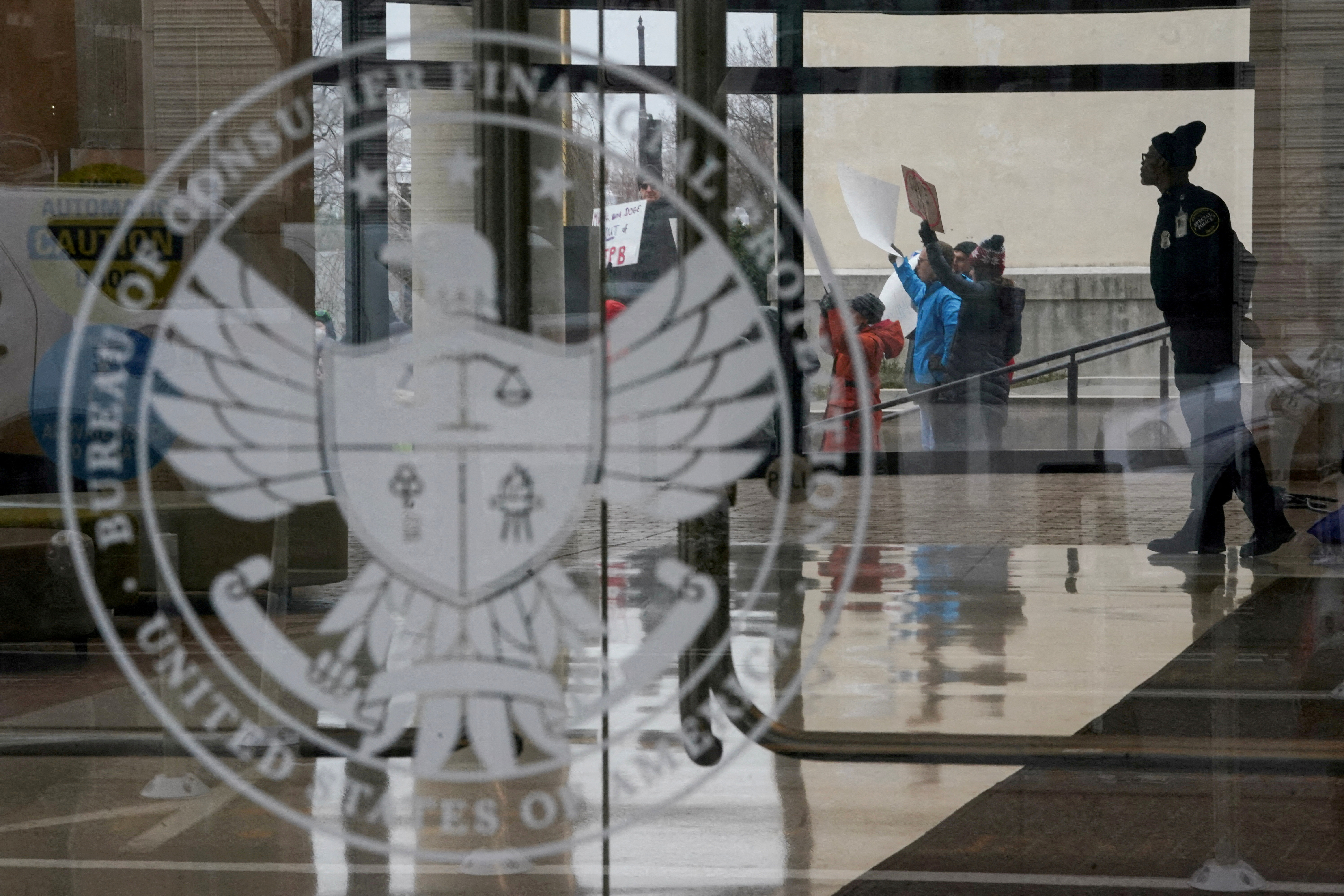 FILE PHOTO: A special police member monitors a protest, while inside the Consumer Financial Protection Bureau (CFPB) building, the day after members of Elon Musk's Department of Government Efficiency (DOGE) moved into the CFPB, in Washington, U.S. February 8, 2025. REUTERS/Nathan Howard/File Photo