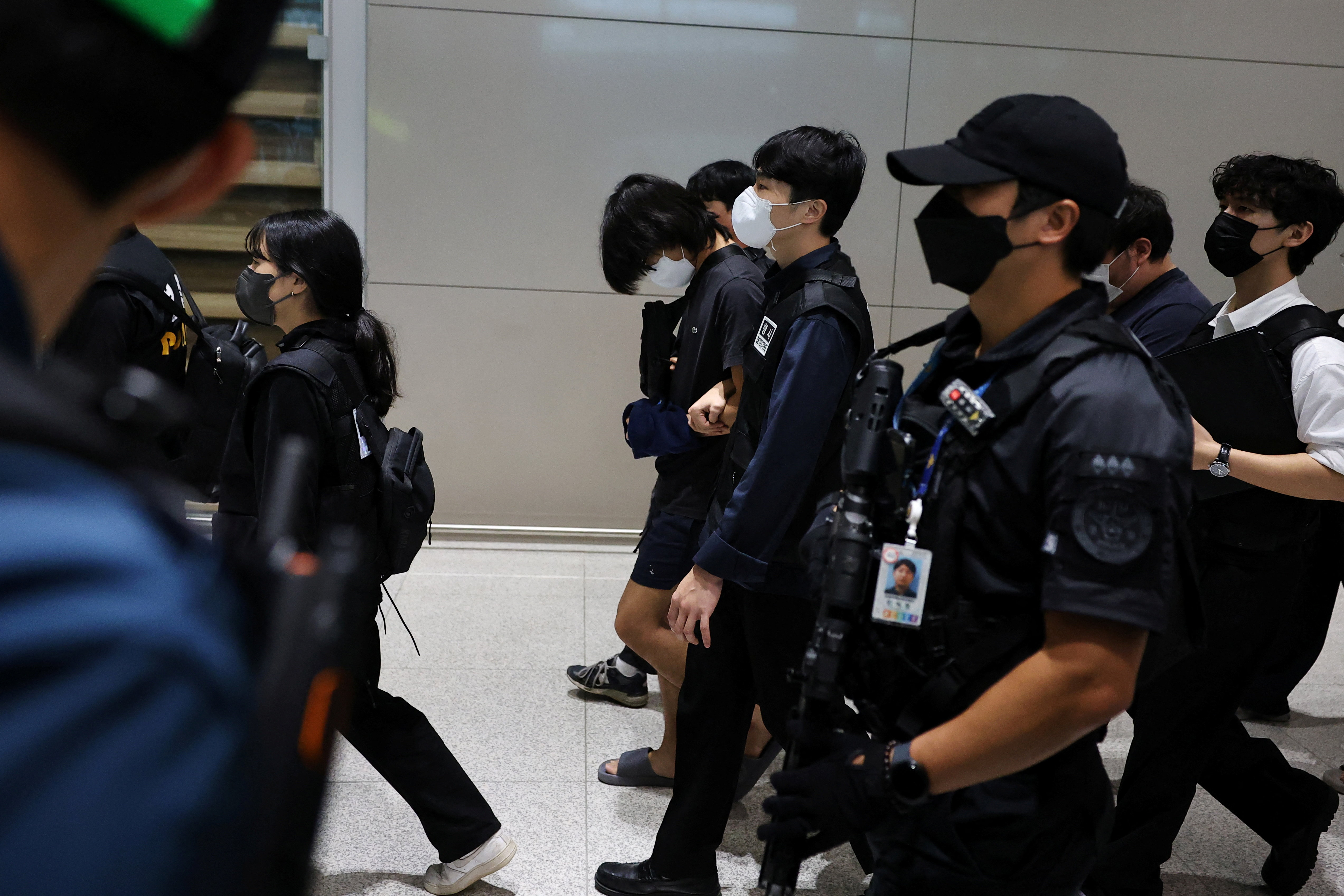 Police officers escort South Korean deportees.