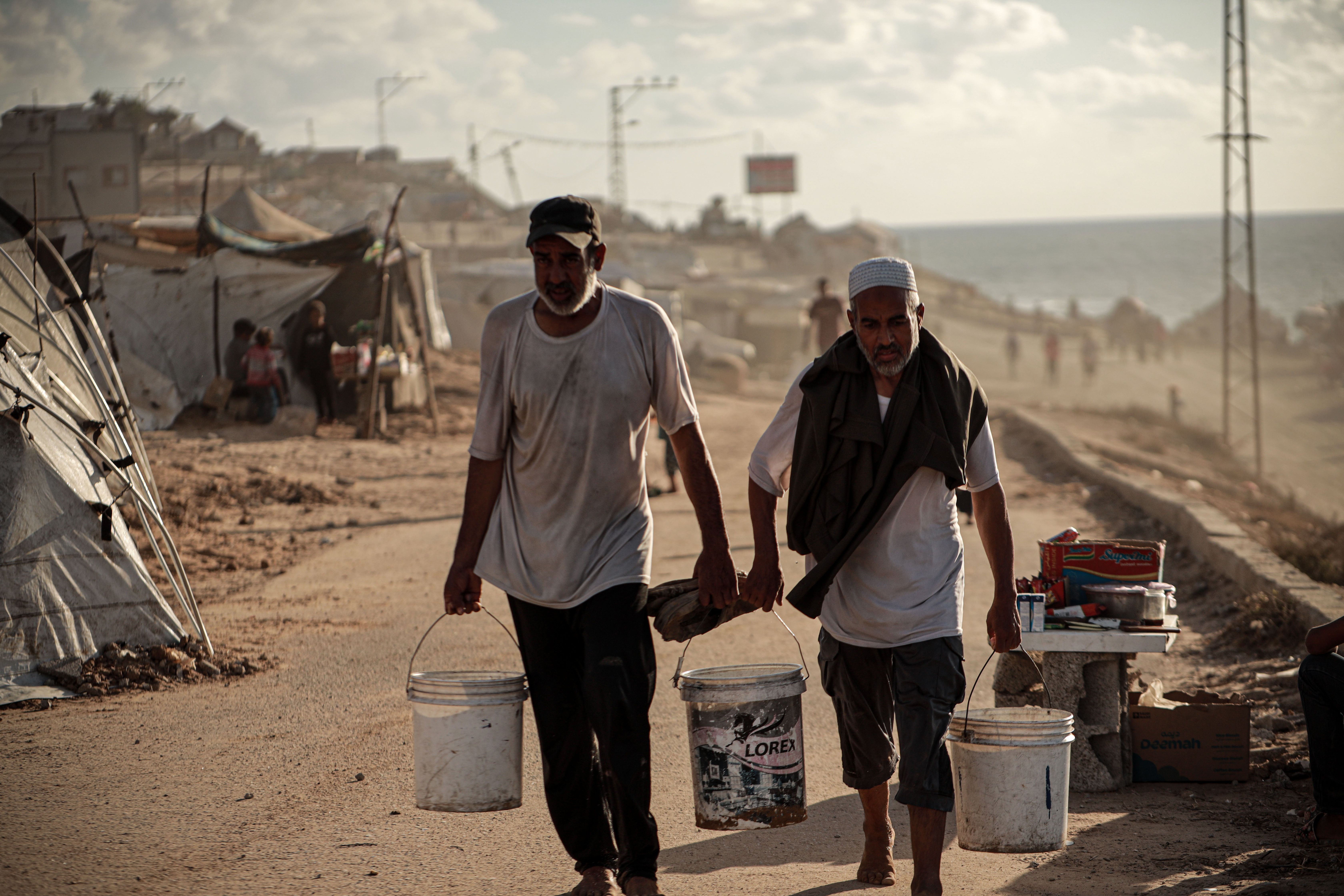 Two men carrying buckets of water in a desolate landscape