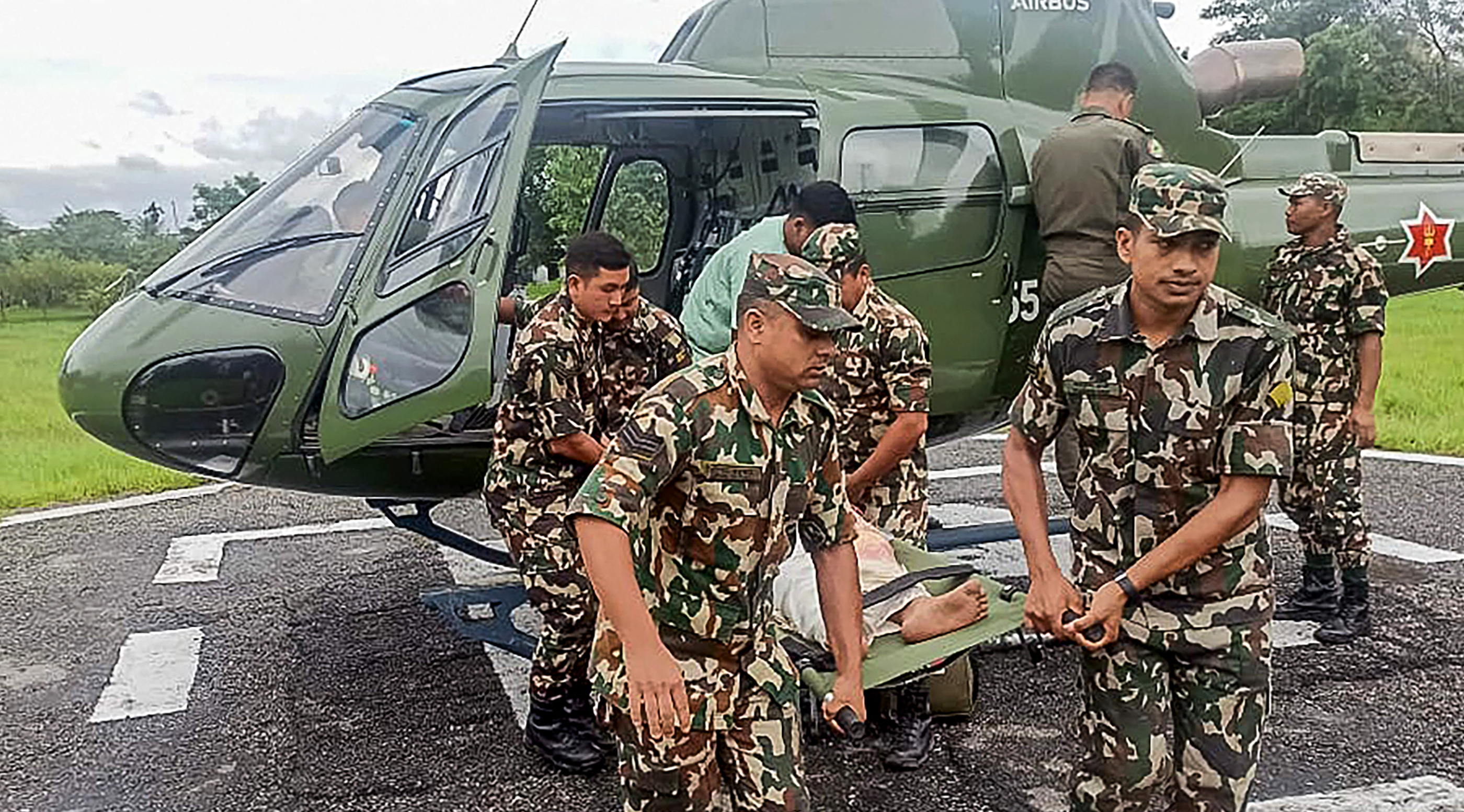 Army personnel carry a landslide victim evacuated by a helicopter following heavy rain-triggered landslides and floods in Nepal