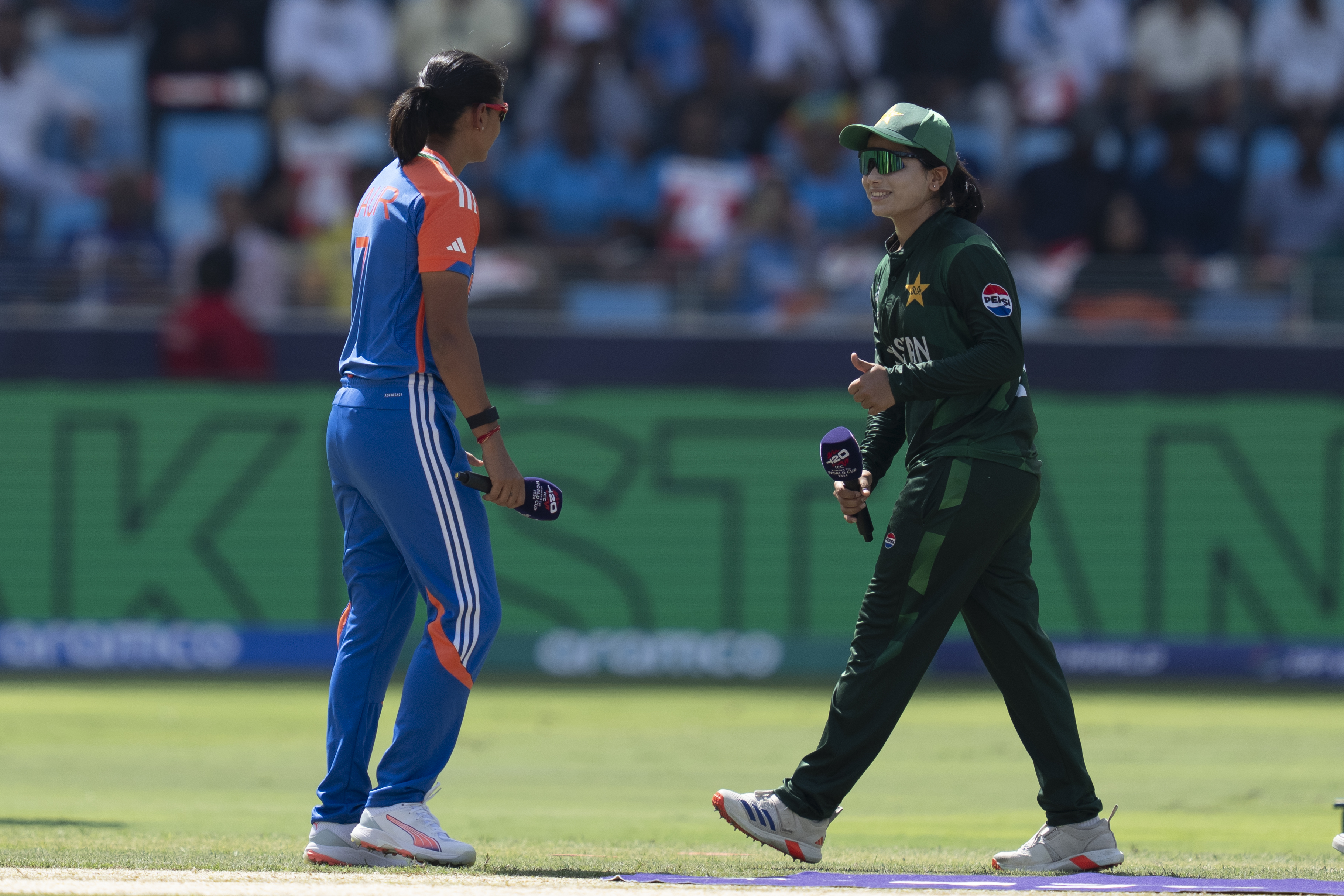 Pakistan's captain Fatima Sana, right, shows thumbs up to her Indian counterpart Harmanpreet Kaur after winning the toss before the start of the ICC Women's T20 World Cup 2024 match between Pakistan and India at Dubai International Stadium, United Arab Emirates, Sunday, Oct. 6, 2024. (AP Photo/Altaf Qadri)