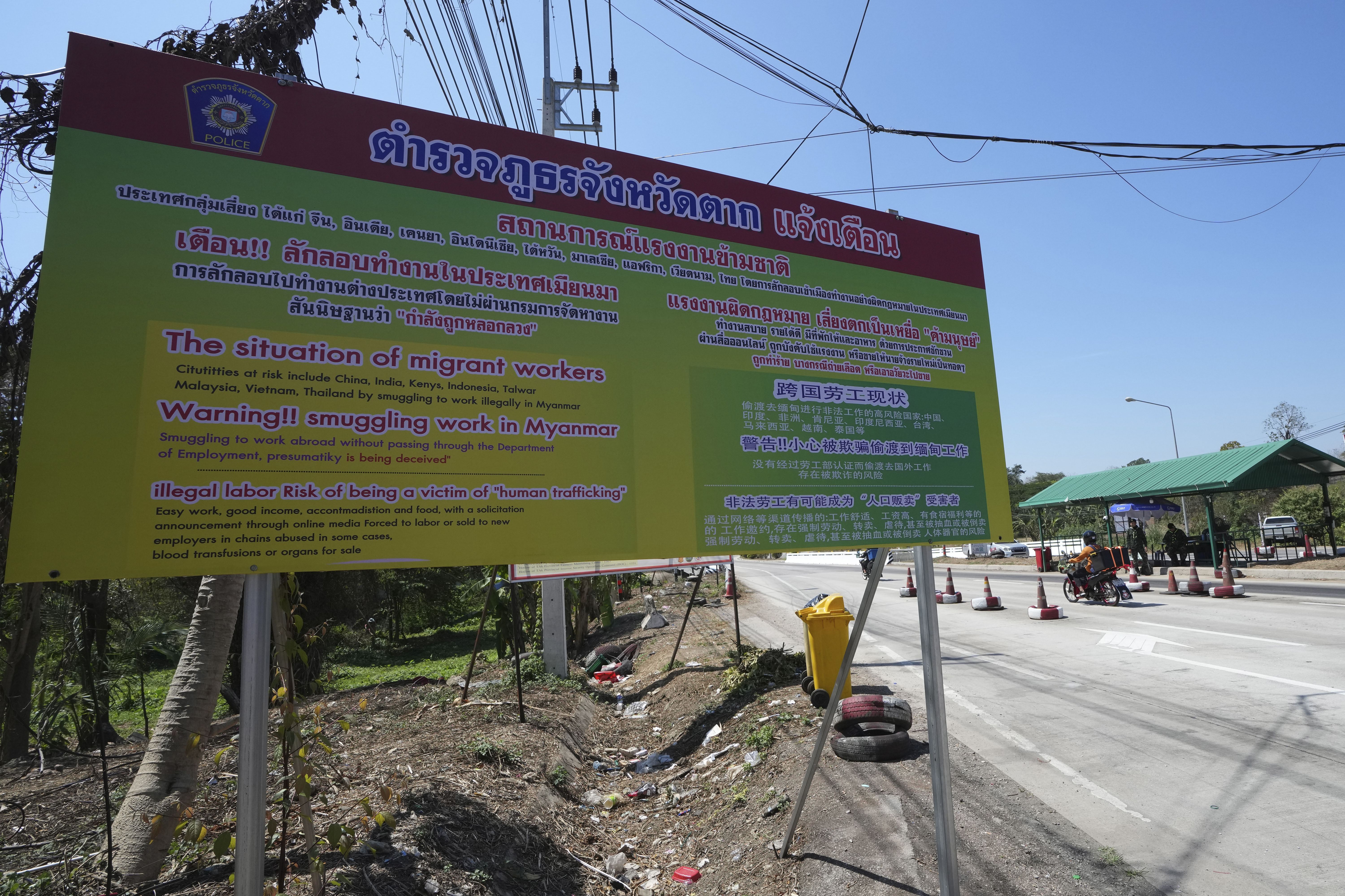 A sign near a military checkpoint in Mae Sot, Thailand, warns in Thai, English and Chinese of the danger of being trafficked and forced to work in locked scam compounds across the Myanmar border, on February 26, 2025 [Sakchai Lalit/AP]