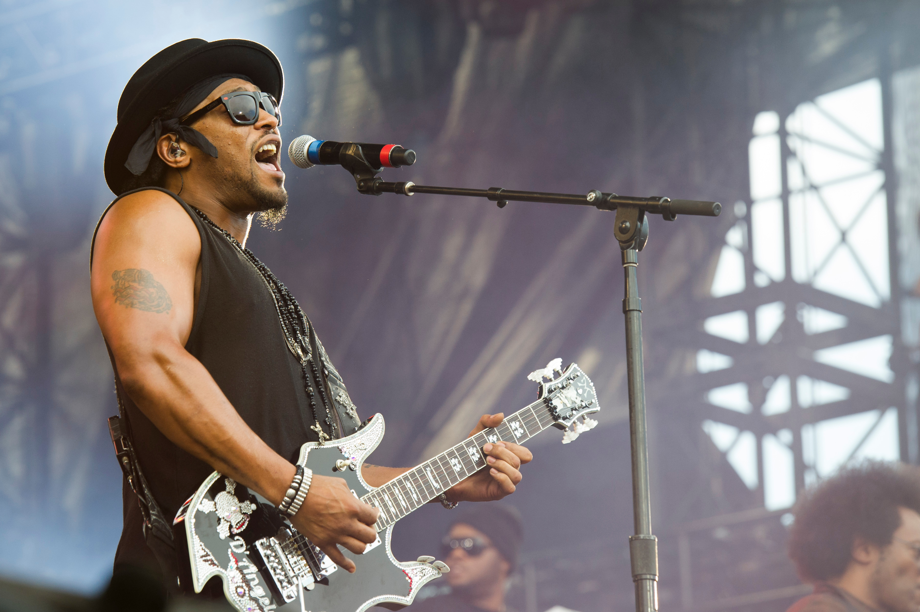 D'Angelo plays guitar and sings into a microphone on stage at the "Made in America" festival