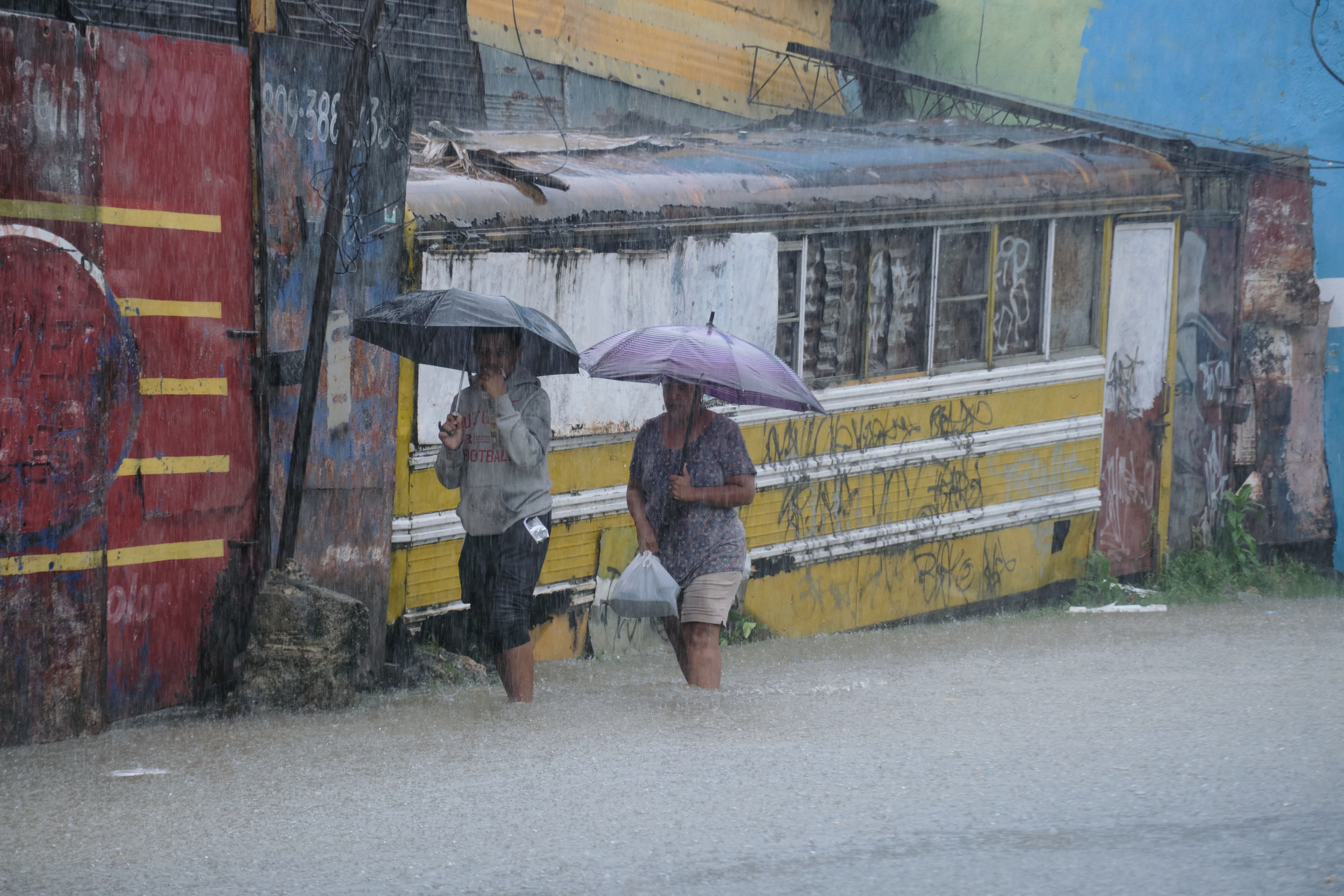 People wade through a street flooded by rains.