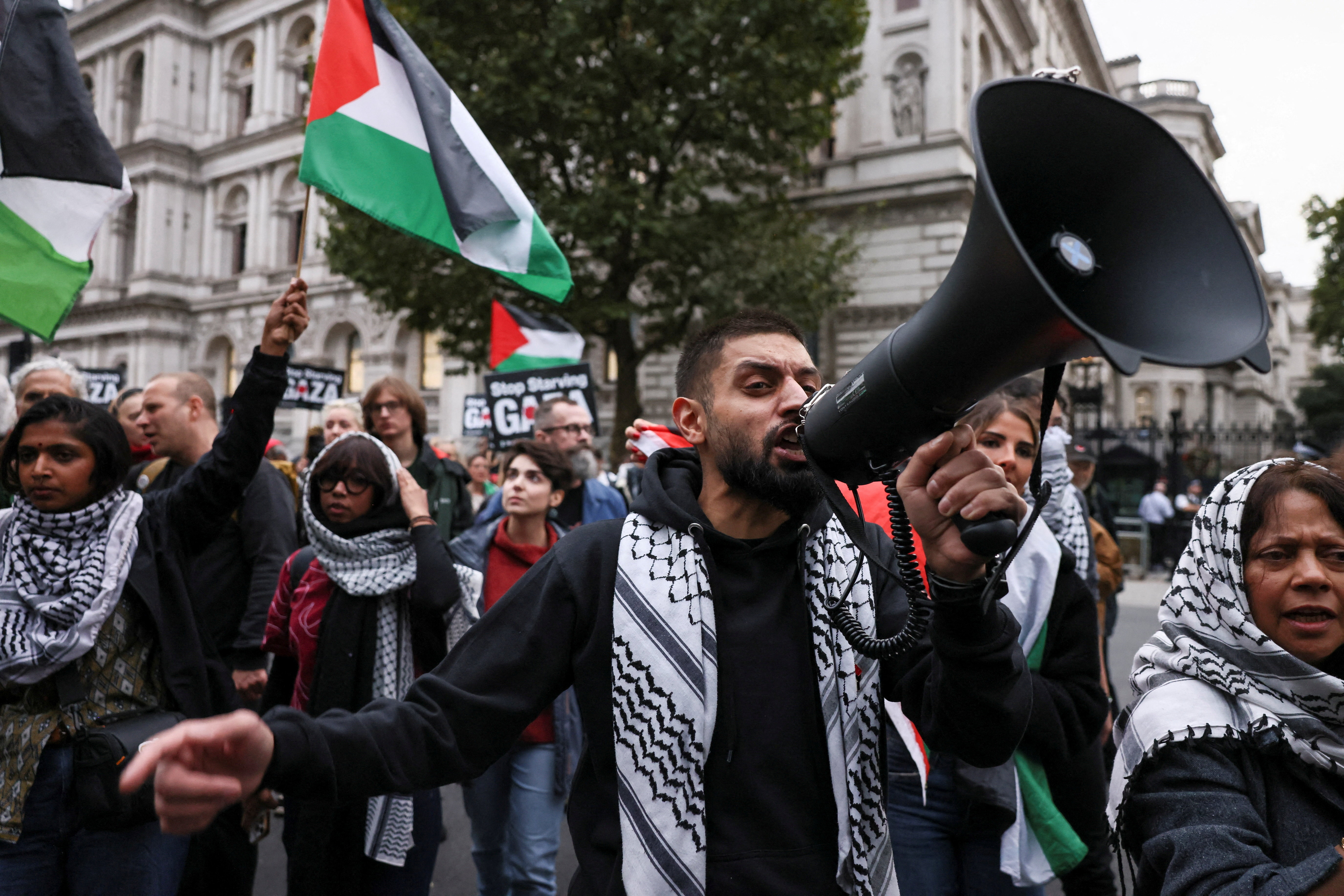 A demonstrator speaks through a megaphone, as people gather in Parliament Square and march along Whitehall to protest and demand protection for the Global Sumud Flotilla, some of whose vessels were intercepted by Israeli forces while carrying aid and activists to Gaza, in London, Britain on Oct. 2, 2025. [Jack Taylor/Reuters]