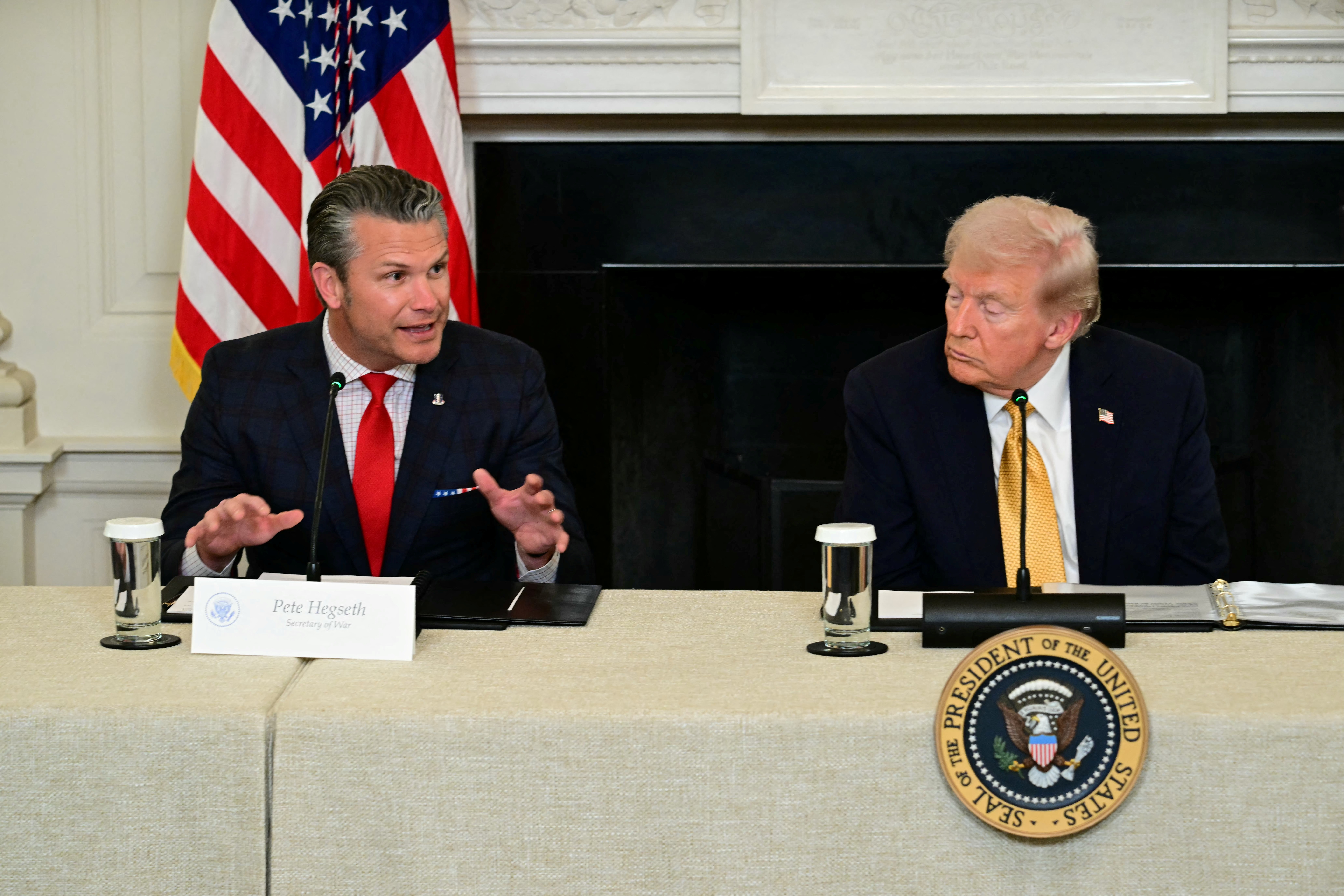 US President Donald Trump (R) listens to Defense Secretary Pete Hegseth (L) in the State Dining Room of the White House on October 23, 2025 in Washington, DC. (Photo by Jim WATSON / AFP)