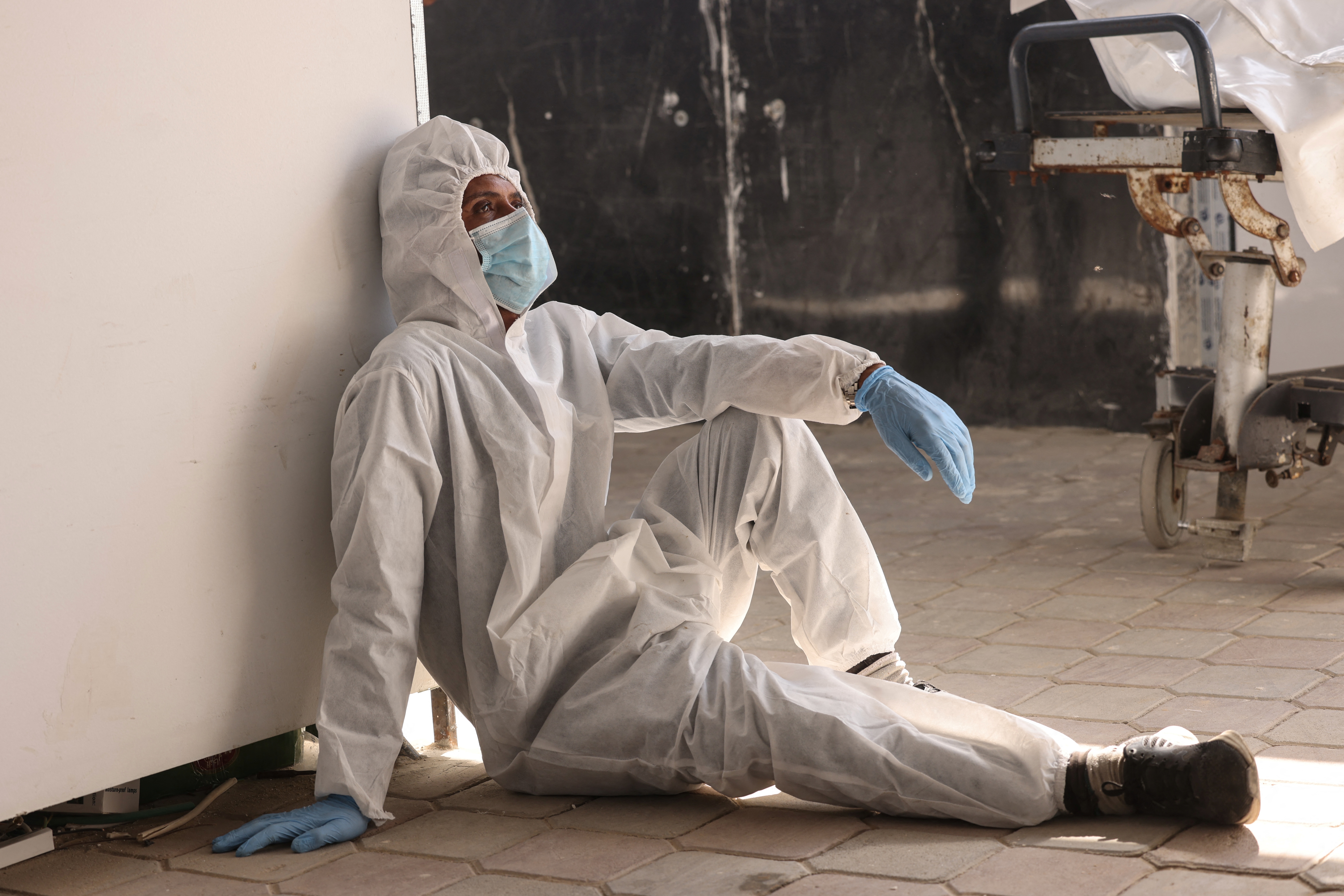 An employee of the Nasser Medical Complex sits on the ground resting after the unloading of body bags containing the thirty corpses of Palestinian prisoners detained by Israel and released as part of the hostage exchange deal, in Khan Yunis, in the southern Gaza Strip, on October 31, 2025.
