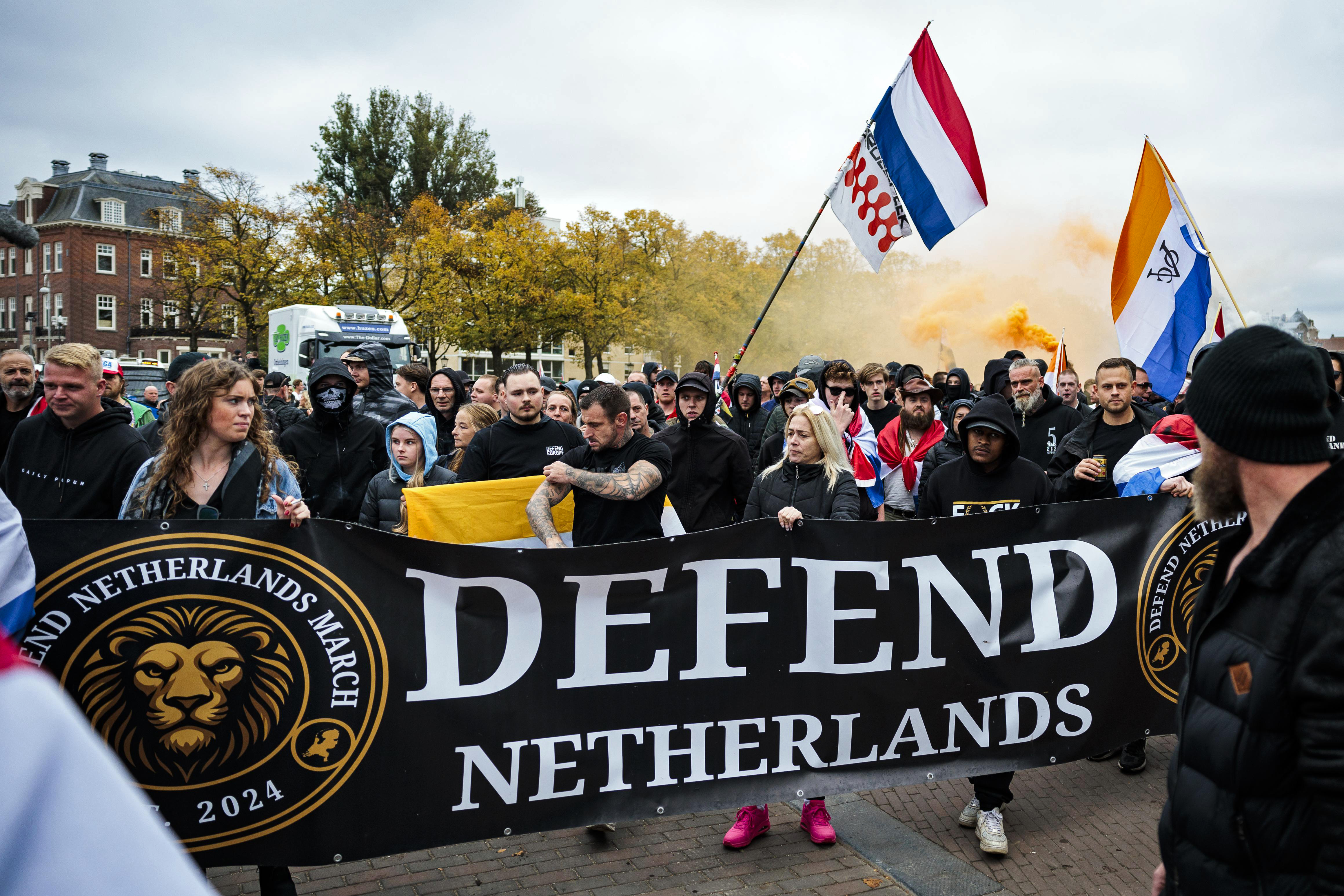 epa12448358 People hold a banner reading 'defend the Netherlands' and wave Dutch flags during an anti-immigration rally under the slogan 'against mass immigration, for a safe Netherlands, and against the housing shortage', at Museumplein in Amsterdam, the Netherlands, 12 October 2025. EPA/ROBIN VAN LONKHUIJSEN