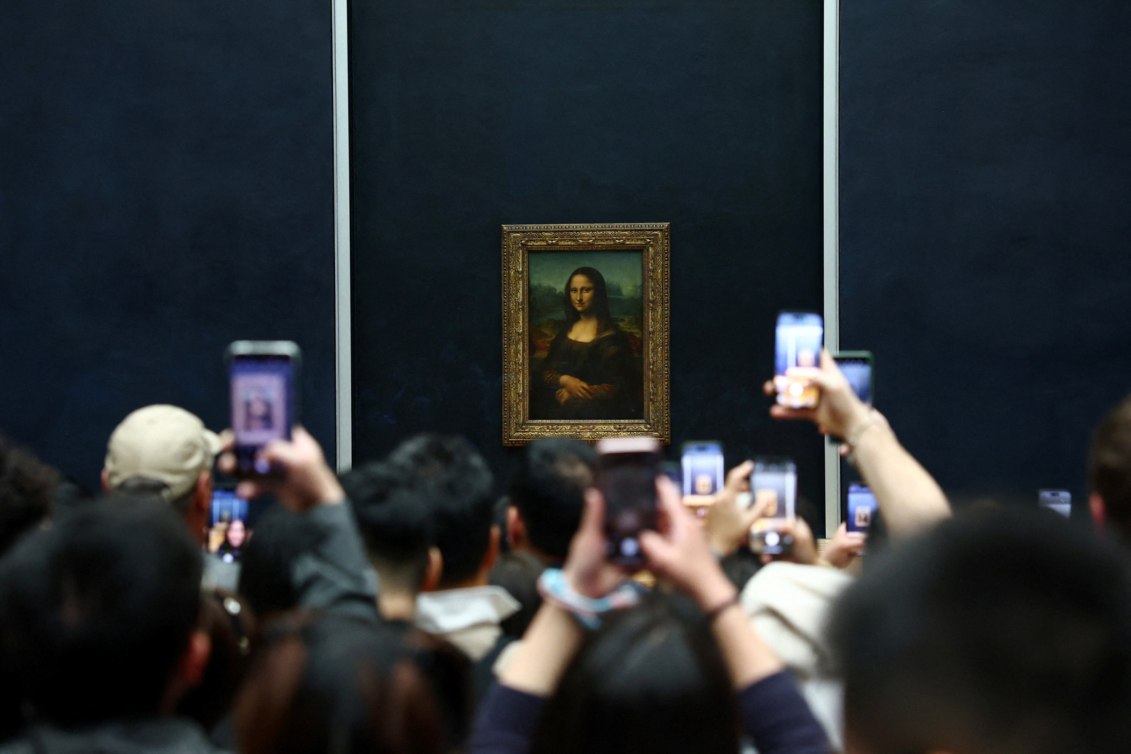 Visitors take pictures of the painting &quot;Mona Lisa&quot; (La Joconde) by Leonardo da Vinci at the Louvre Museum on the day it reopened to the public for the first time since last Sunday&#039;s heist, while the Galerie d&#039;Apollon where eight pieces of Napoleon and the Empress&#039;s jewelry collection displayed in the gallery were stolen by thieves, remains closed, in Paris, France on Oct. 22, 2025. [Gonzalo Fuentes/Reuters]