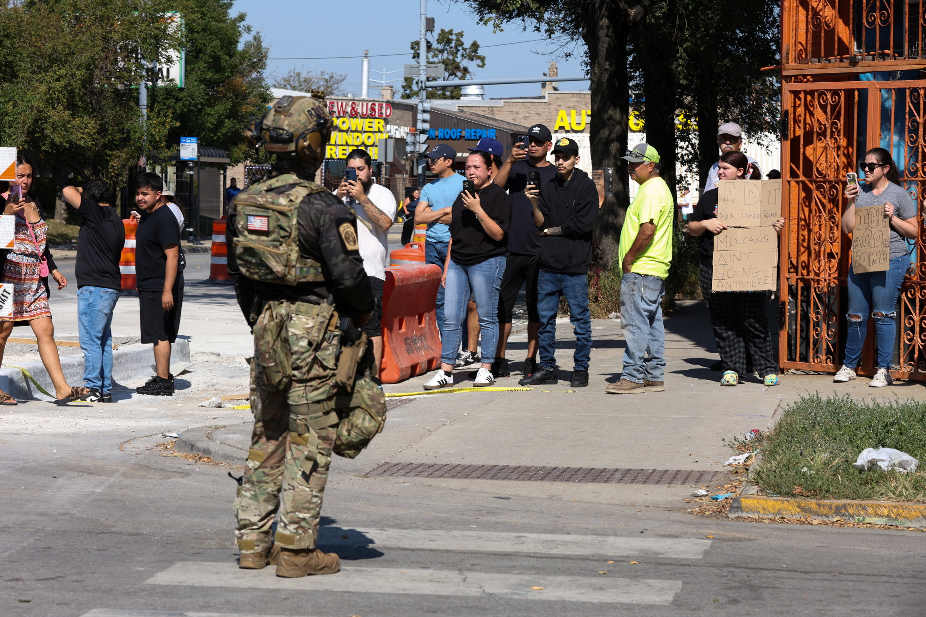 Demonstrators use their phones in front of a law enforcement officer.